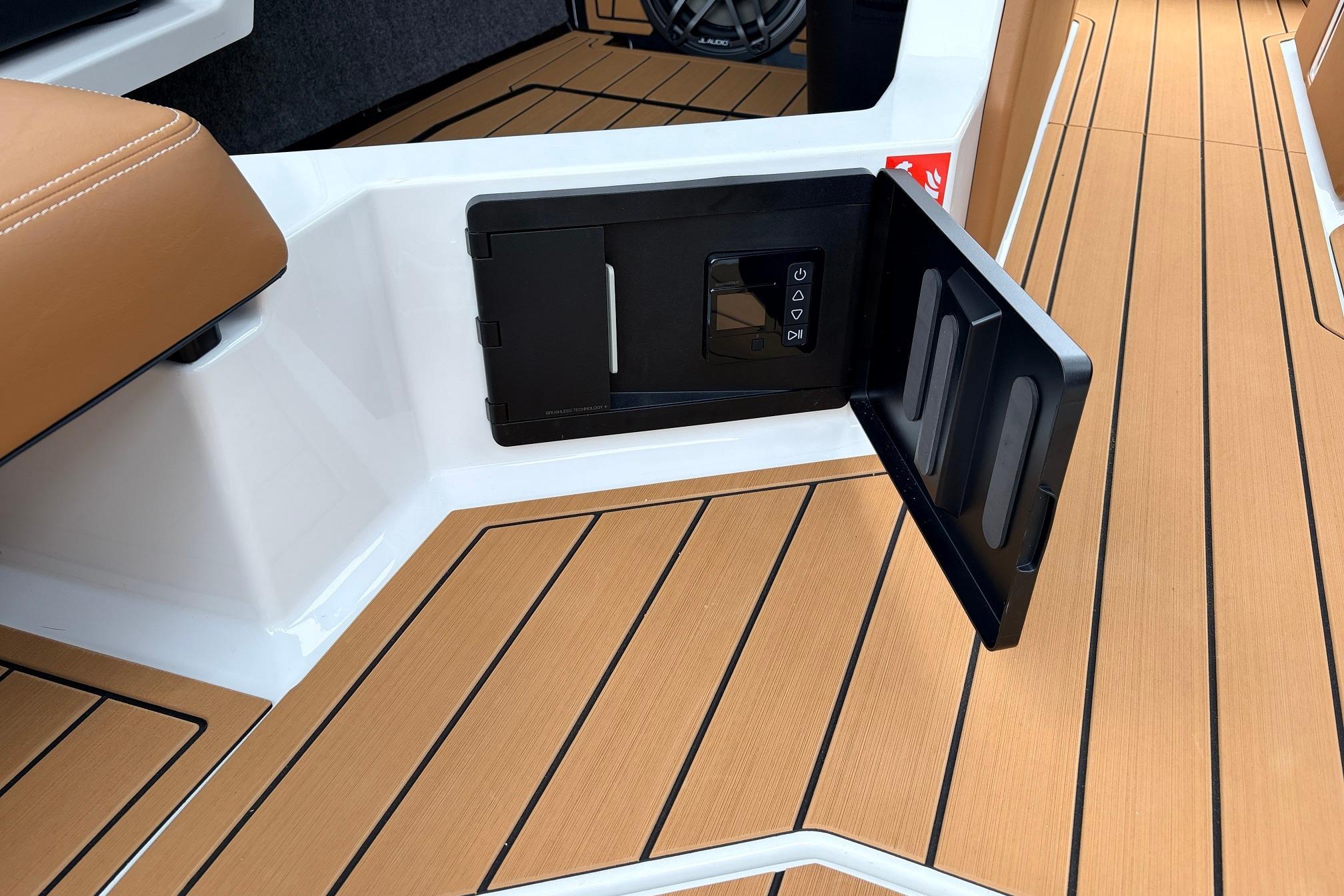 2026 Nautique Super Air Nautique G25 interior with open storage compartment and teak flooring.