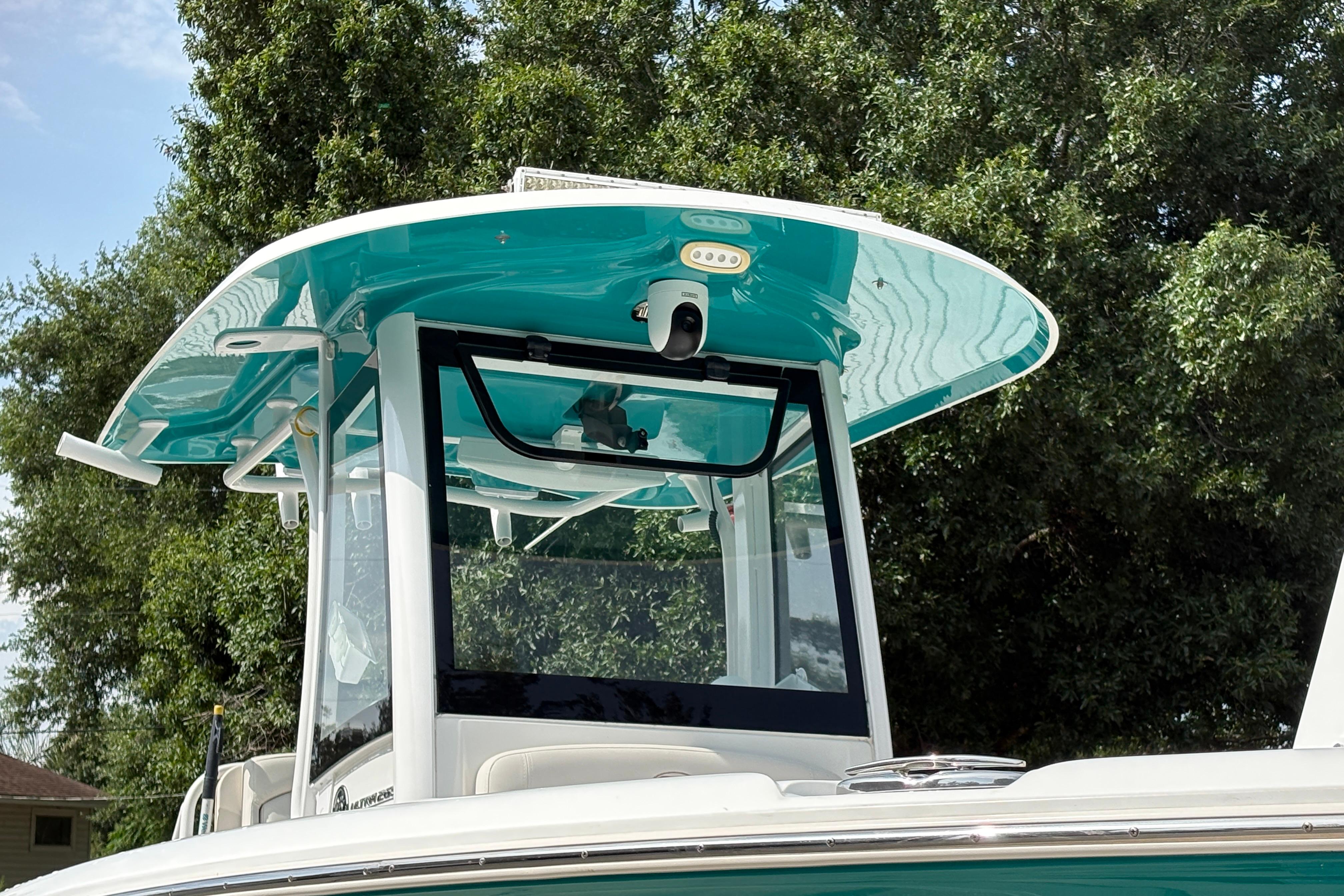 2021 Sea Hunt Ultra 265 SE boat with teal canopy, surrounded by trees.