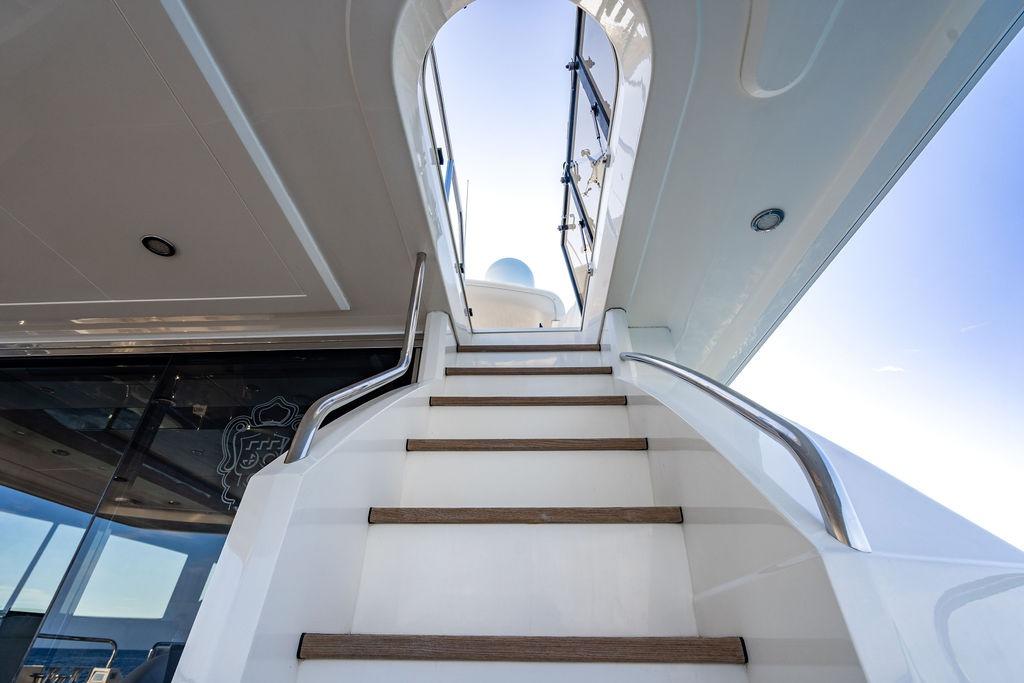 Staircase on 2010 Princess 95 Motor Yacht leading to upper deck under clear sky.