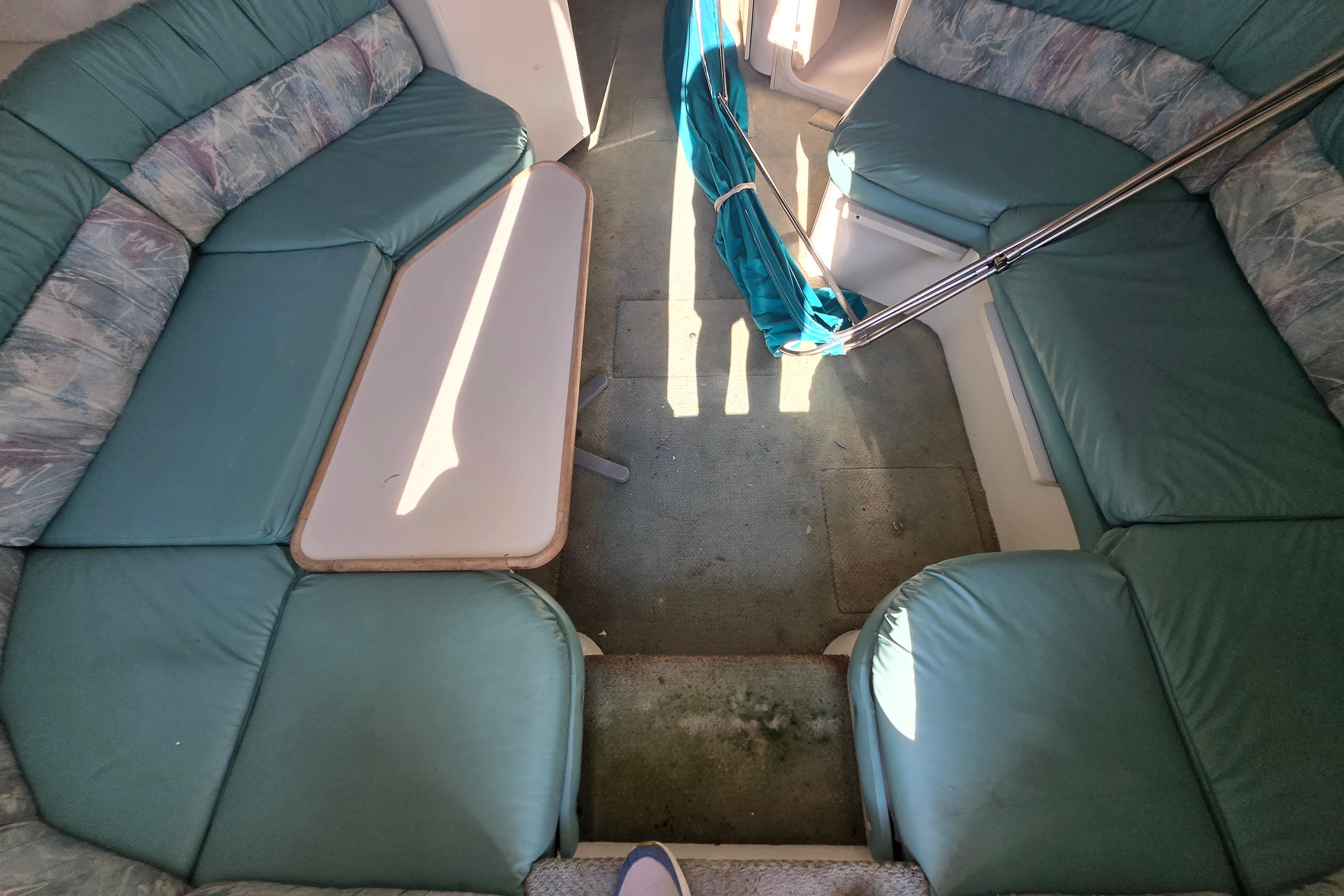Interior of a 1994 Carver 380 Santego yacht with teal seating and a central table.