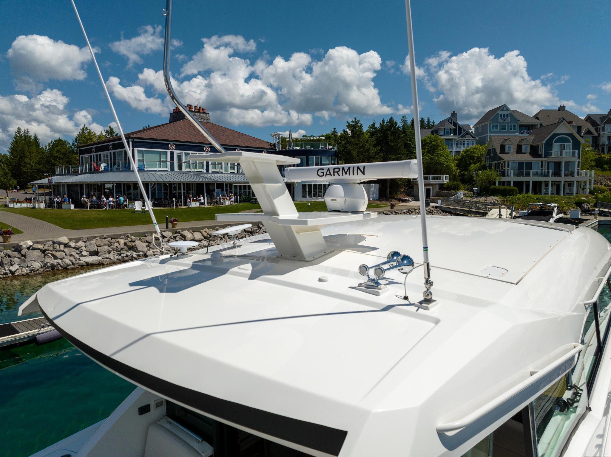 2022 Tiara Yachts C49 Coupe docked near waterfront homes and a clubhouse.