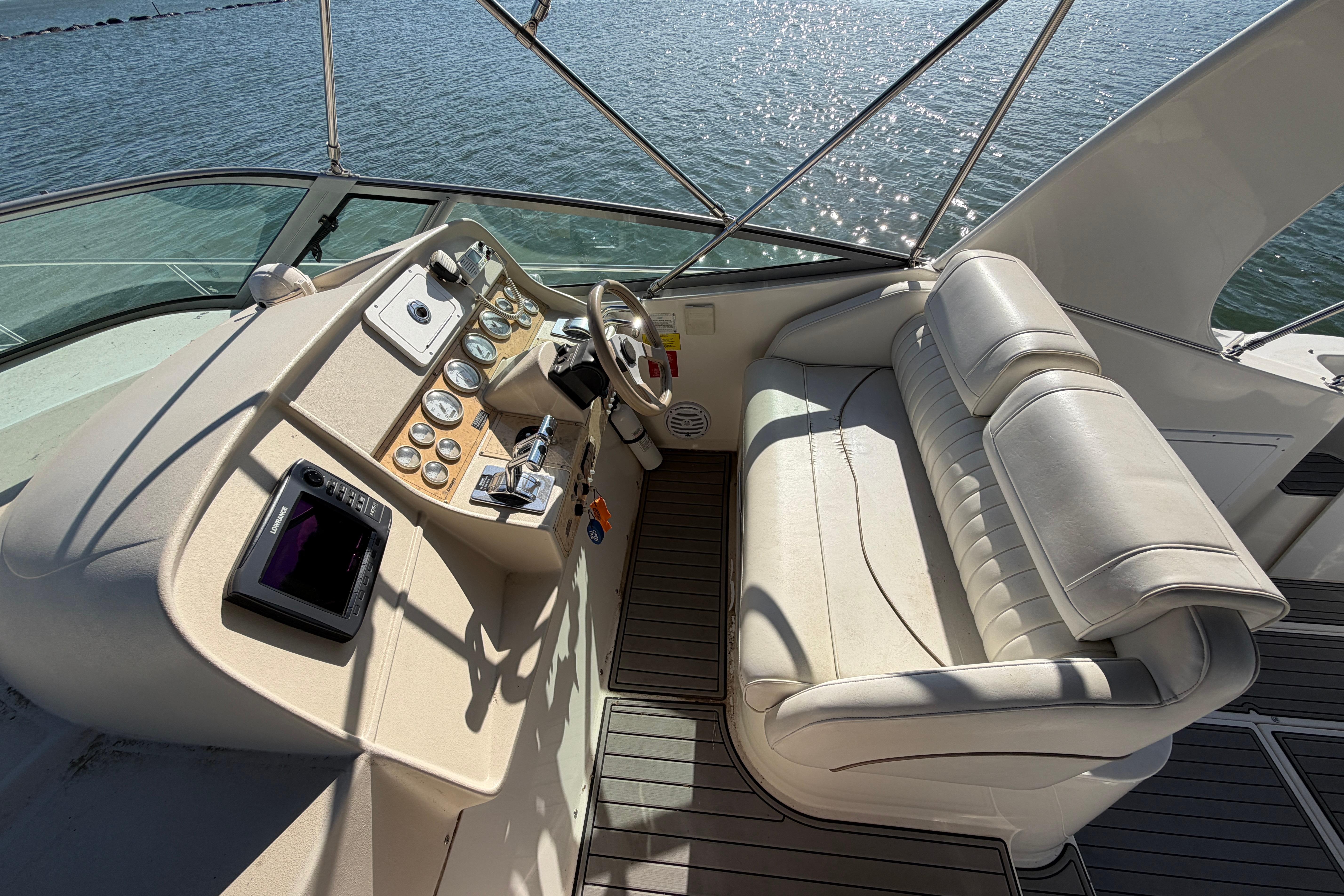1997 Cruisers 3575 yacht helm with white seating and control panel, overlooking water.