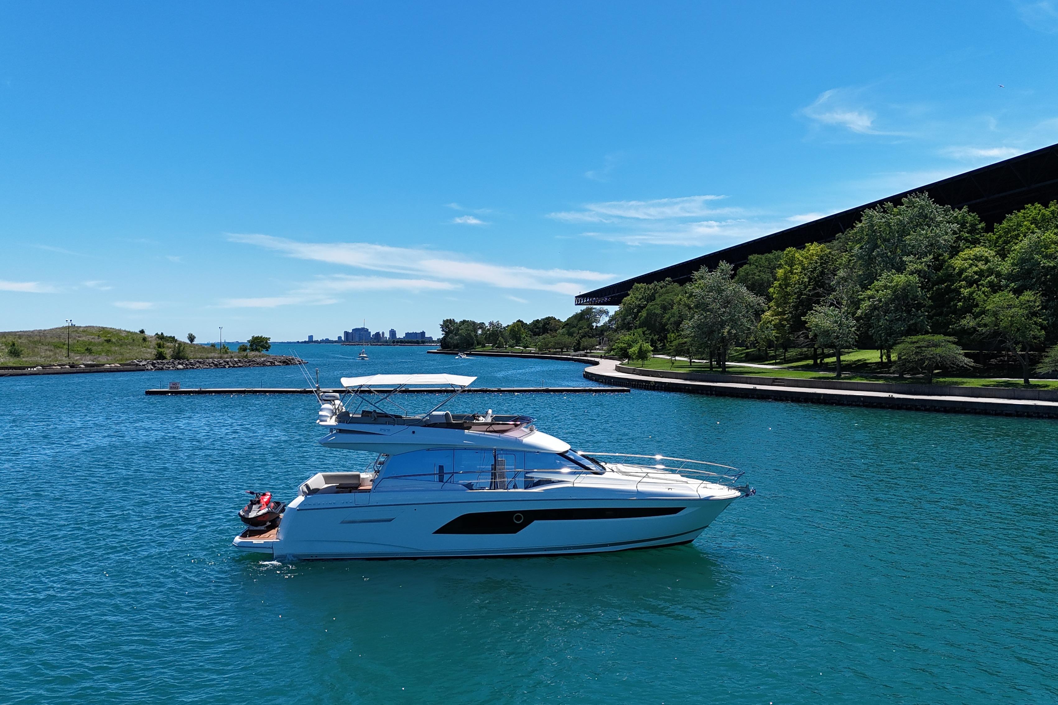 2022 Prestige 520 yacht cruising on a serene blue lake under a clear sky.