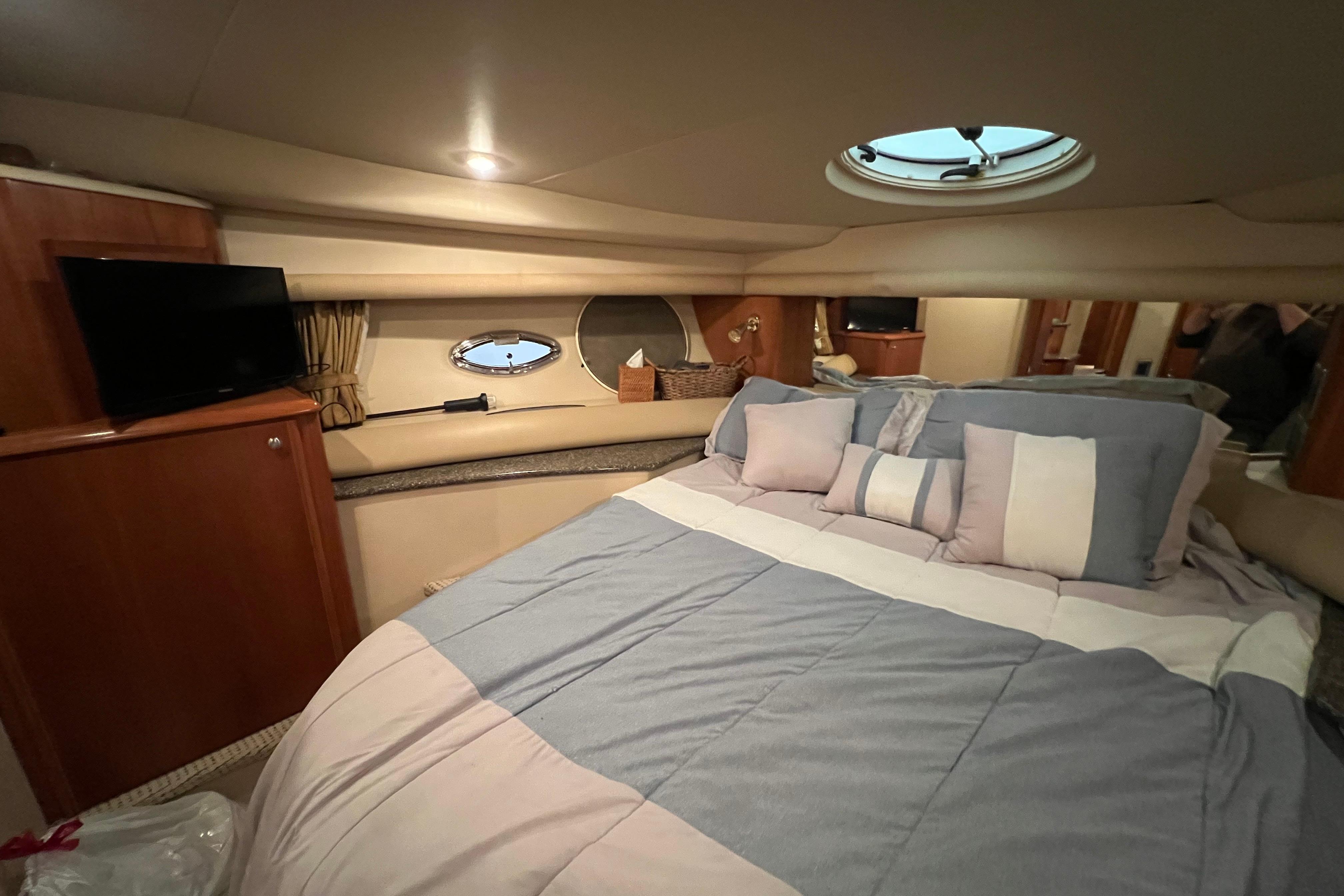 Luxurious bedroom interior of 2004 Meridian 408 Motoryacht with cozy bedding and porthole windows.