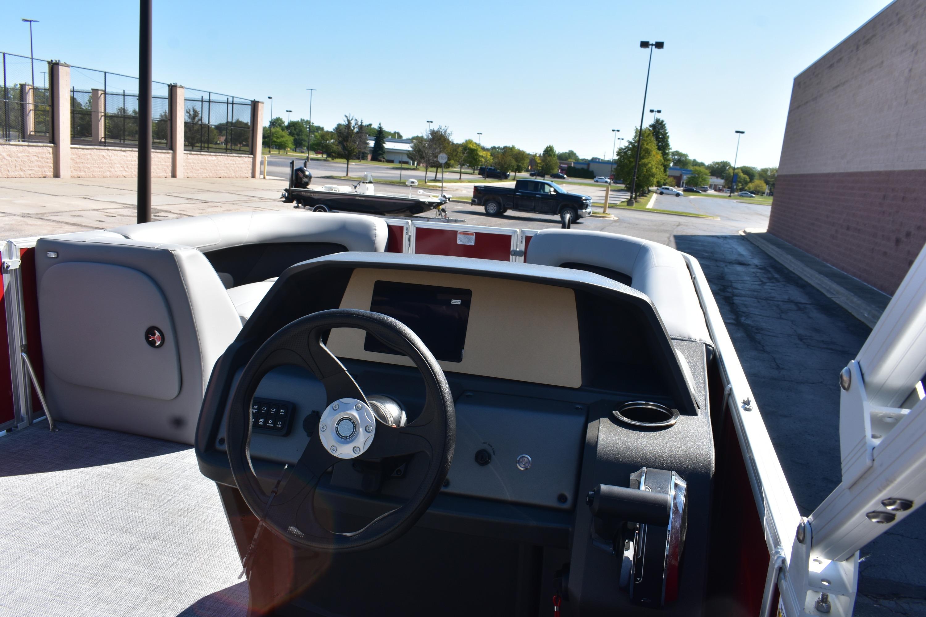 2026 Sun Tracker Party Barge 18 DLX interior with steering wheel and seating in a parking lot.