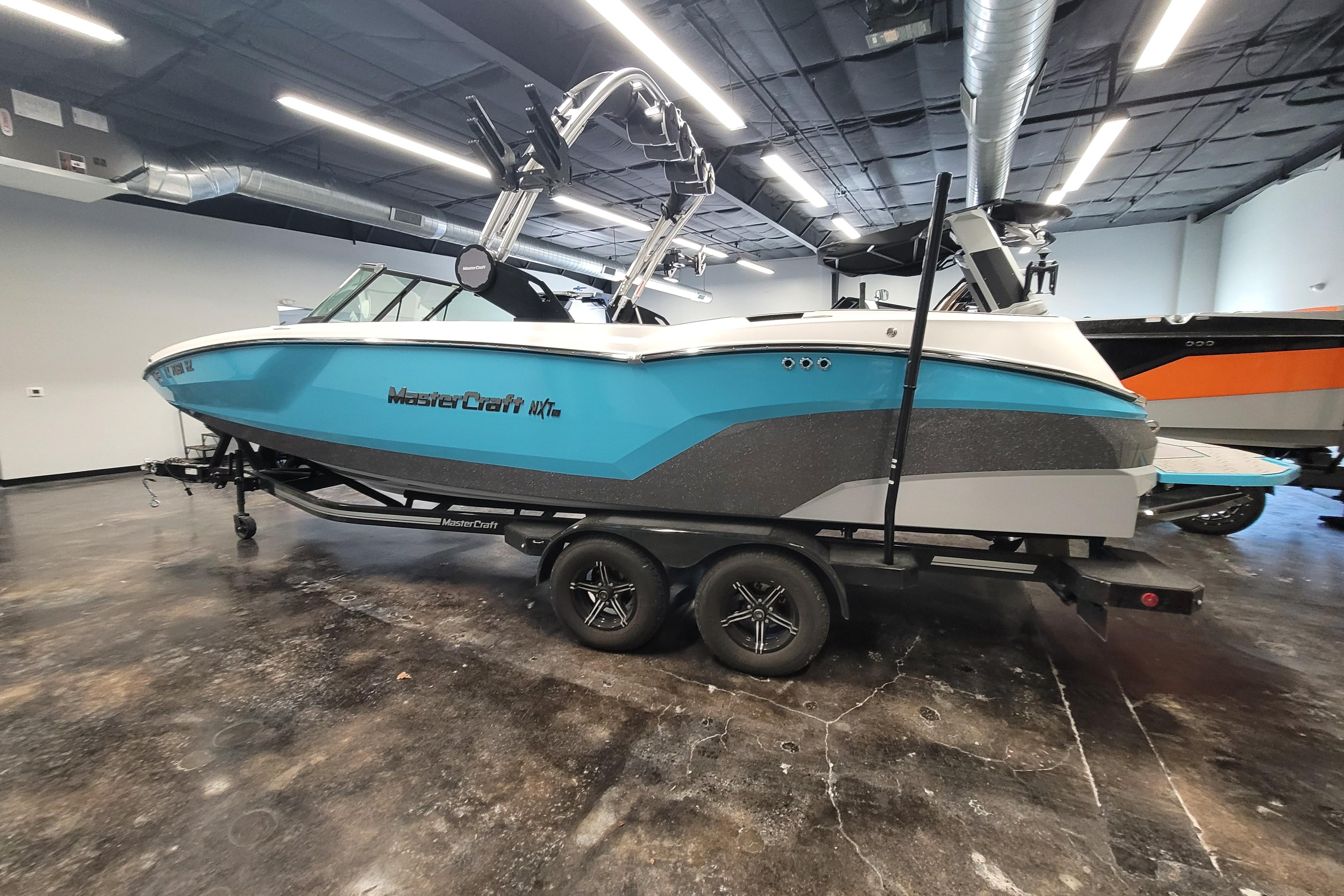 2024 MasterCraft NXT24 boat in showroom, blue and gray design on trailer.