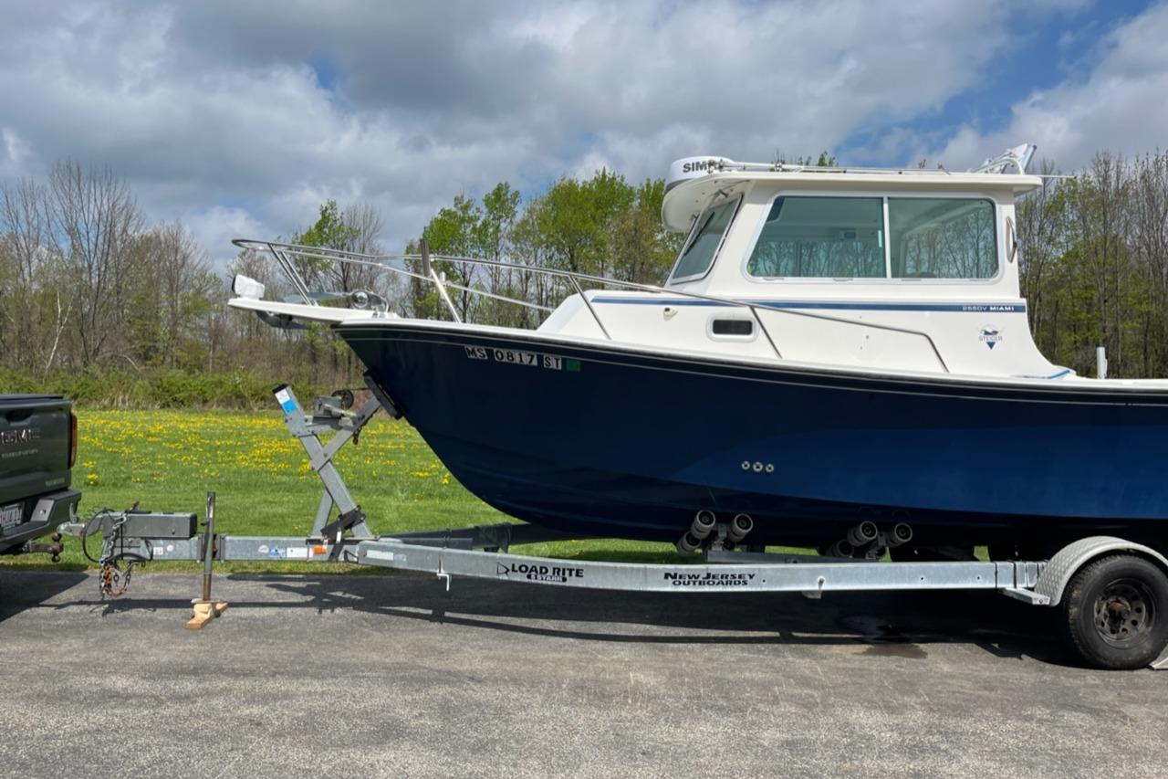 2012 Steiger Craft Miami boat on trailer, parked outdoors under cloudy sky.