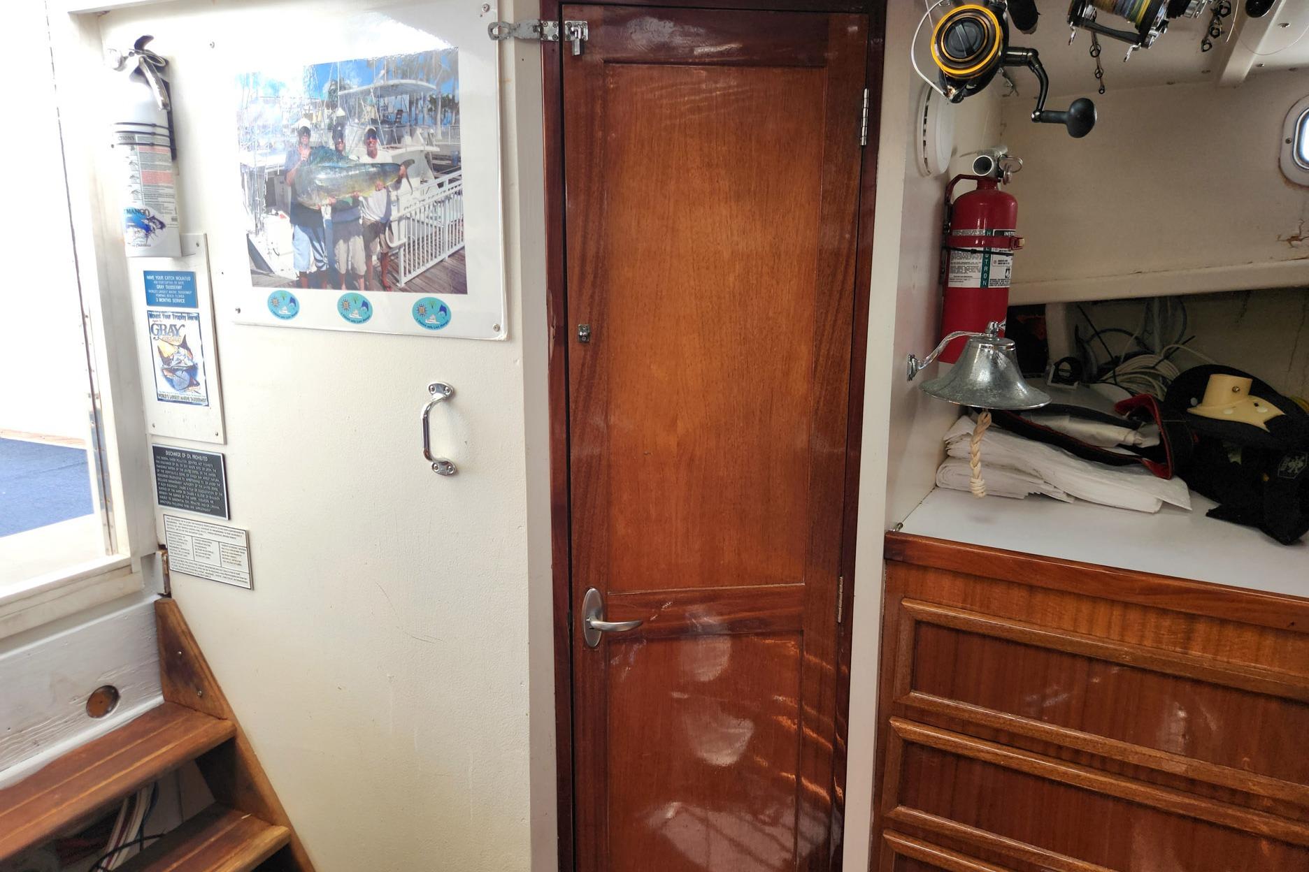 Interior of 1987 Young Brothers Custom Sport Fish boat with wooden door and fishing gear.