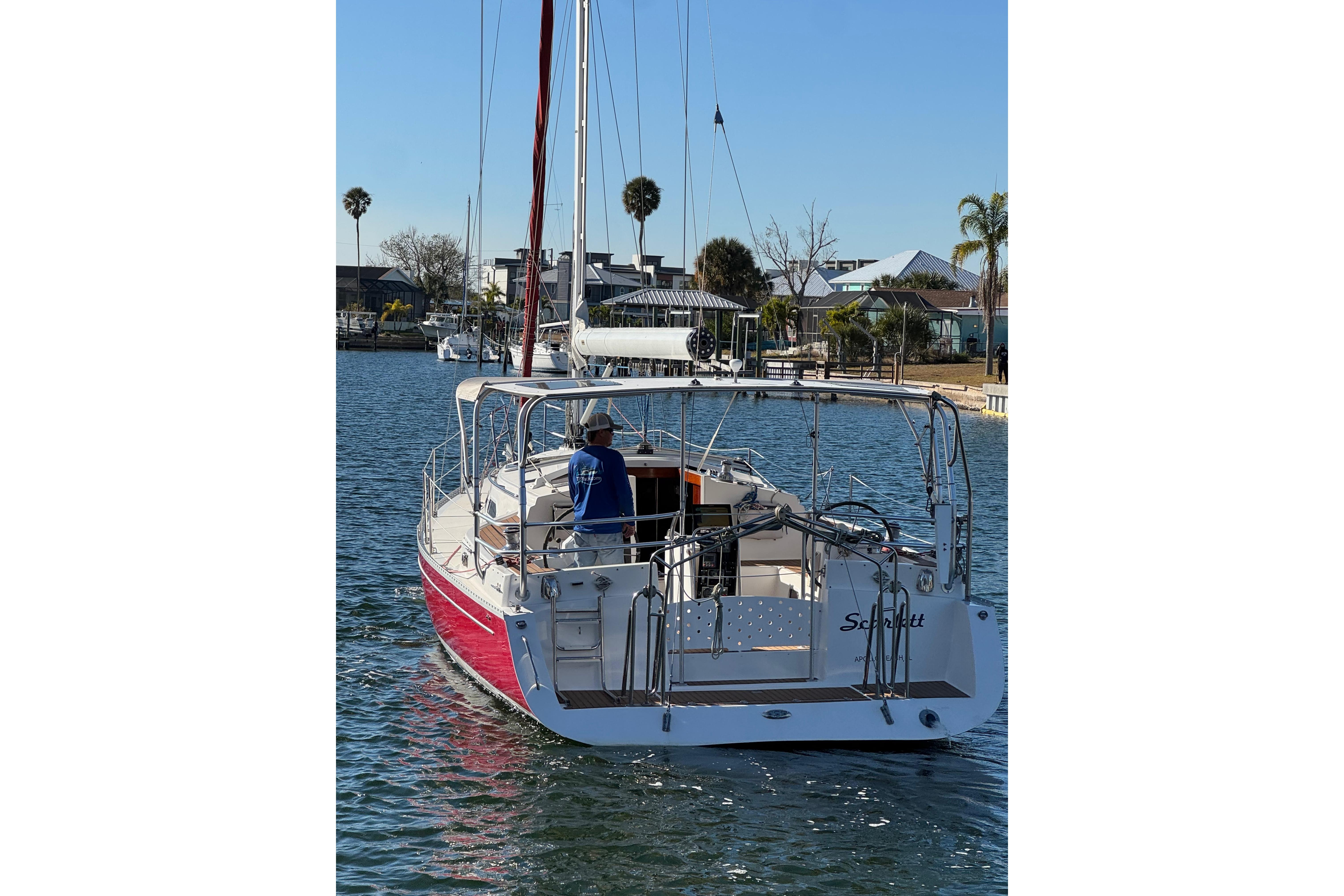 2006 Shannon Shoalsailer sailboat on calm water, with a person onboard, near a residential area.
