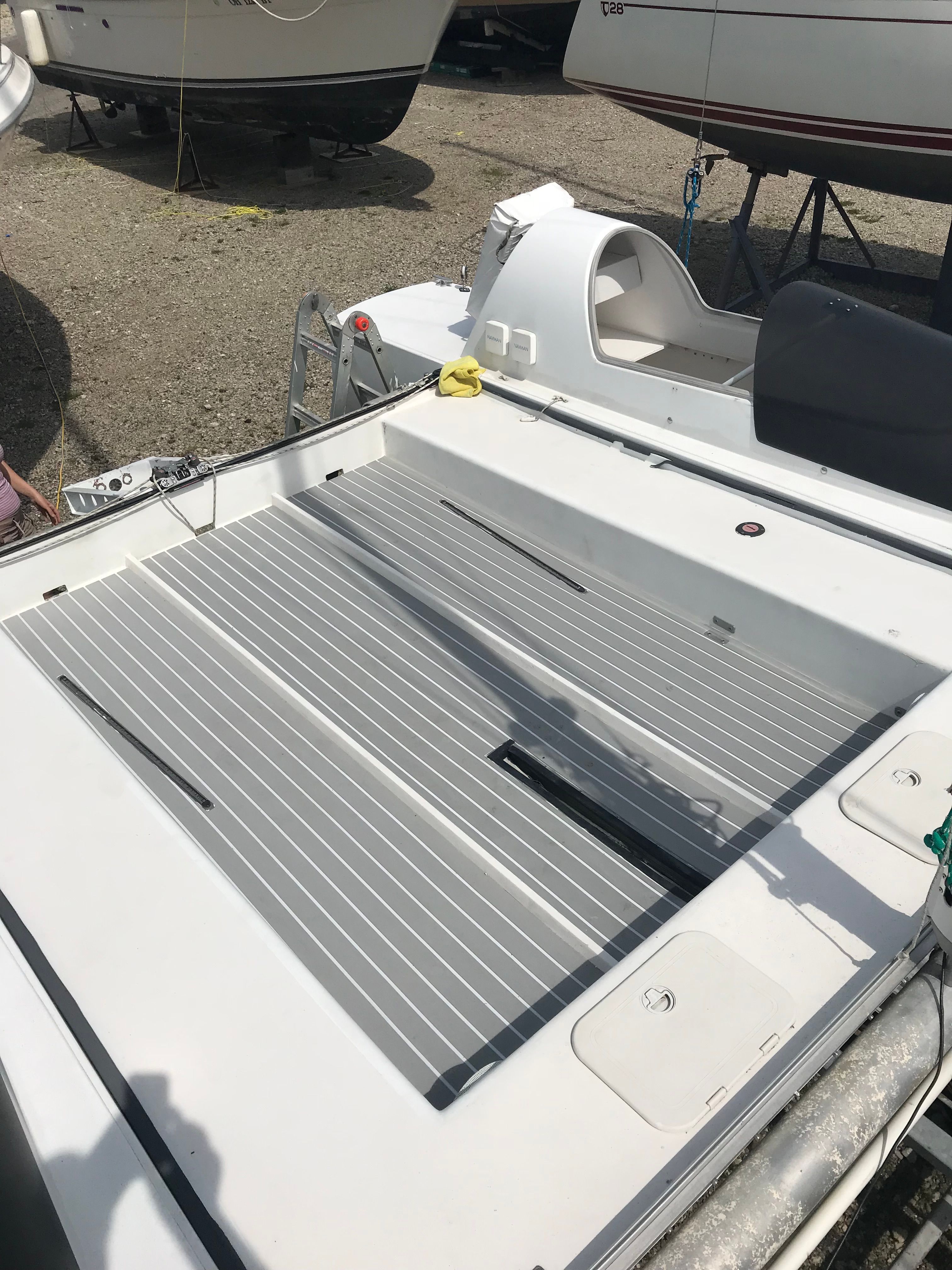 The image shows the deck of a catamaran with gray stripes and white details.