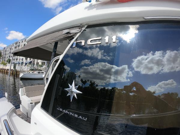 2017 Jeanneau NC 11 boat reflecting sky and clouds on water.