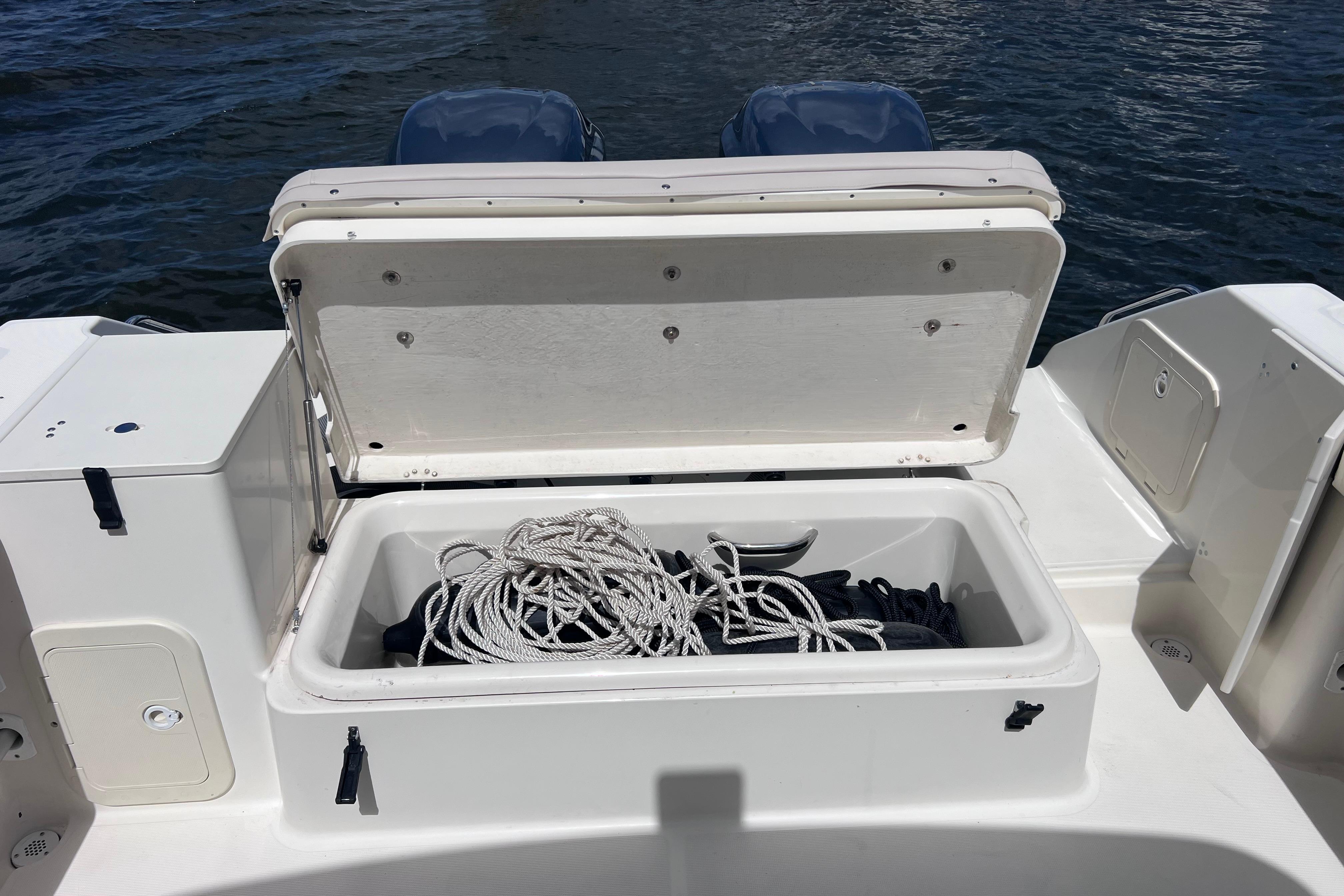 Open storage compartment on 2004 Pursuit 2870 Walkaround boat with coiled rope inside.