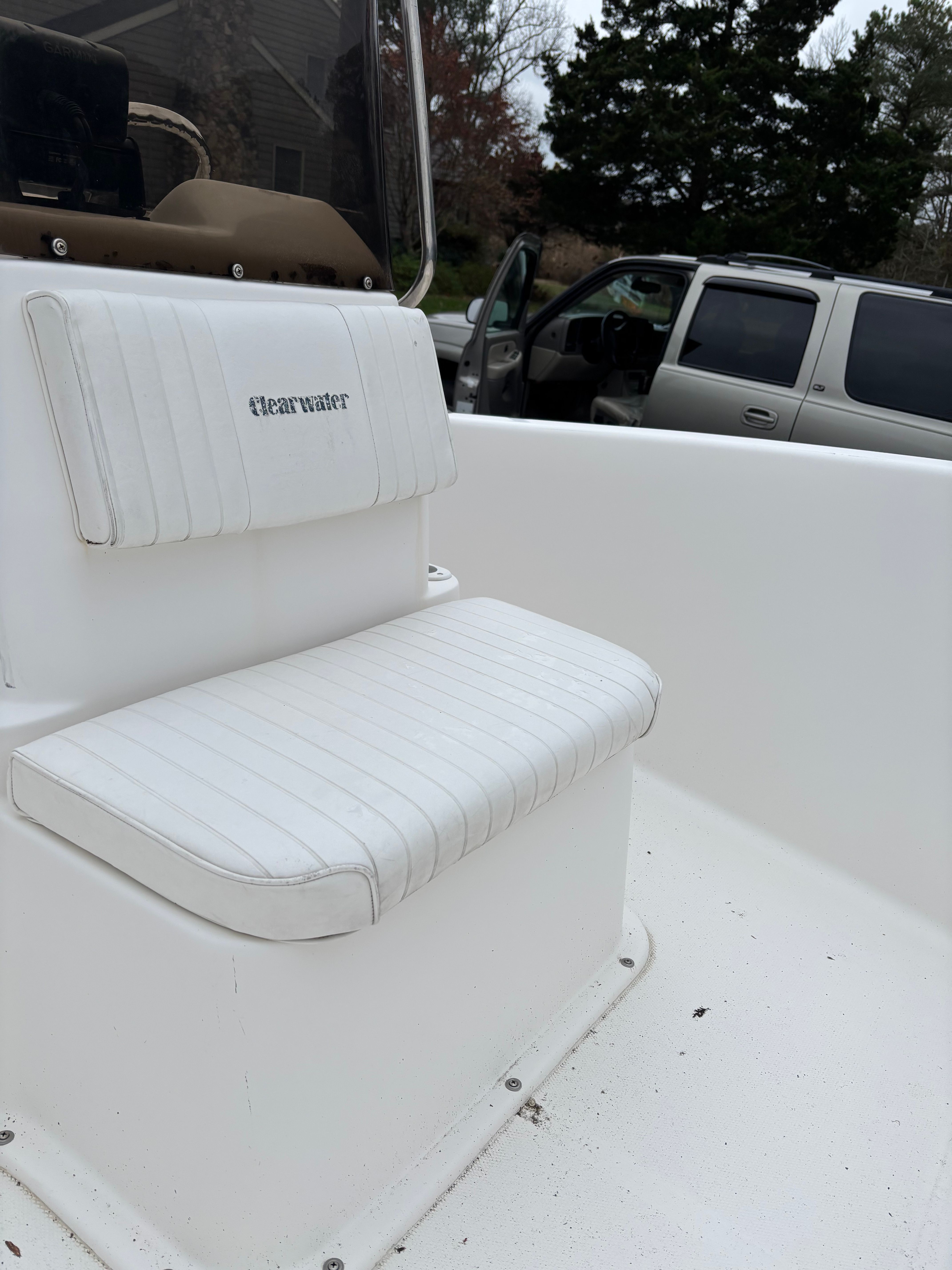 A white seat on a Clearwater boat, parked next to a car.