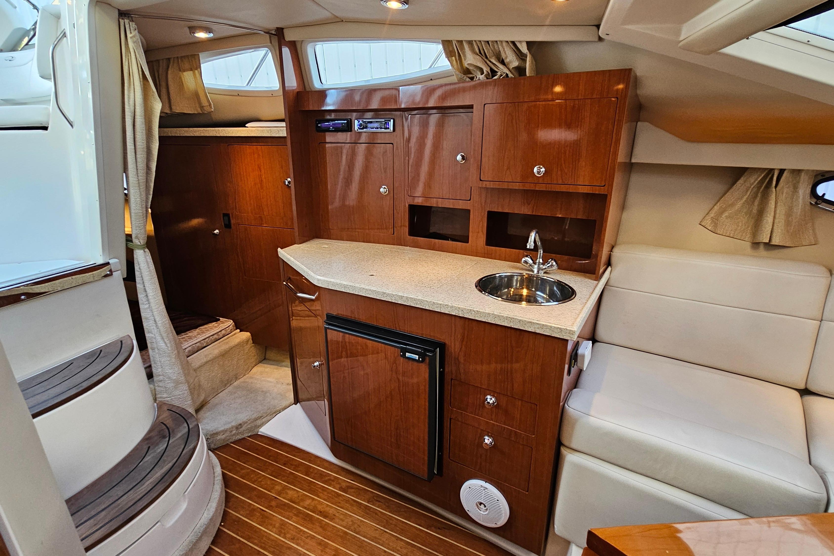 2005 Regal 3060 Window Express cabin interior with kitchenette, wood cabinetry, and seating area.