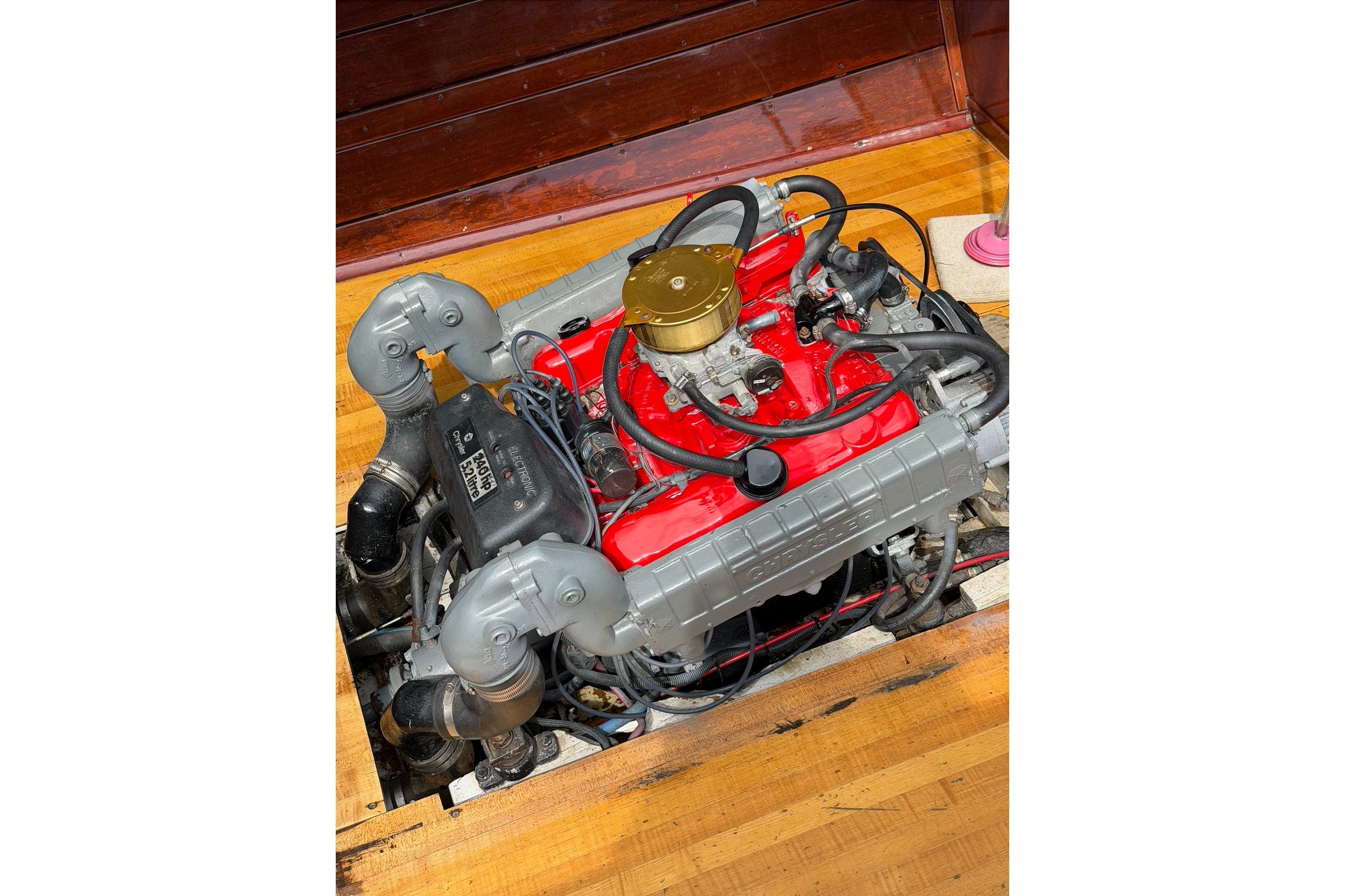 1964 Lyman 25 Sleeper boat engine with red and gray components, displayed on wooden flooring.