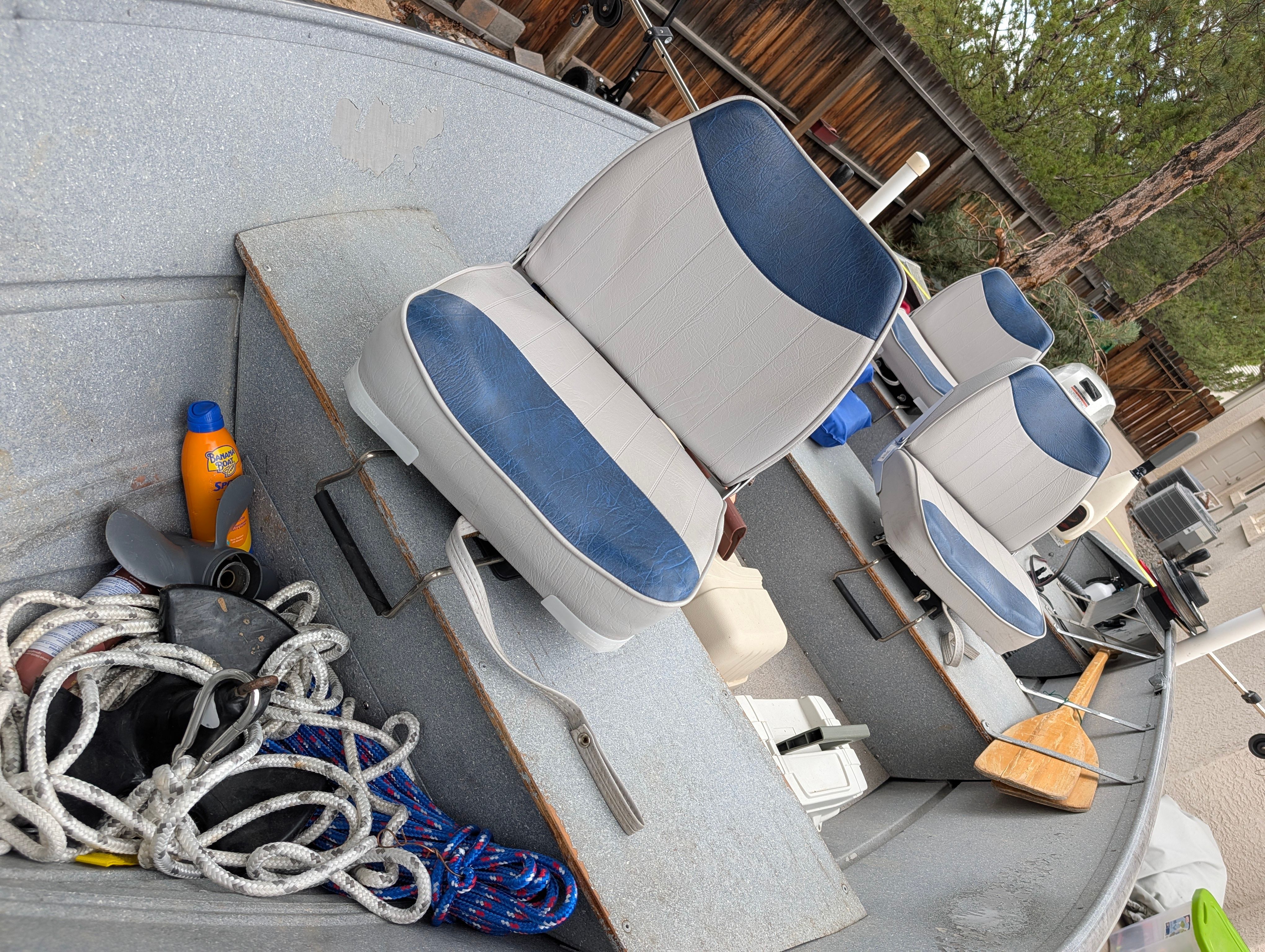 Interior view of a boat with blue and white seats, ropes, and a paddle.