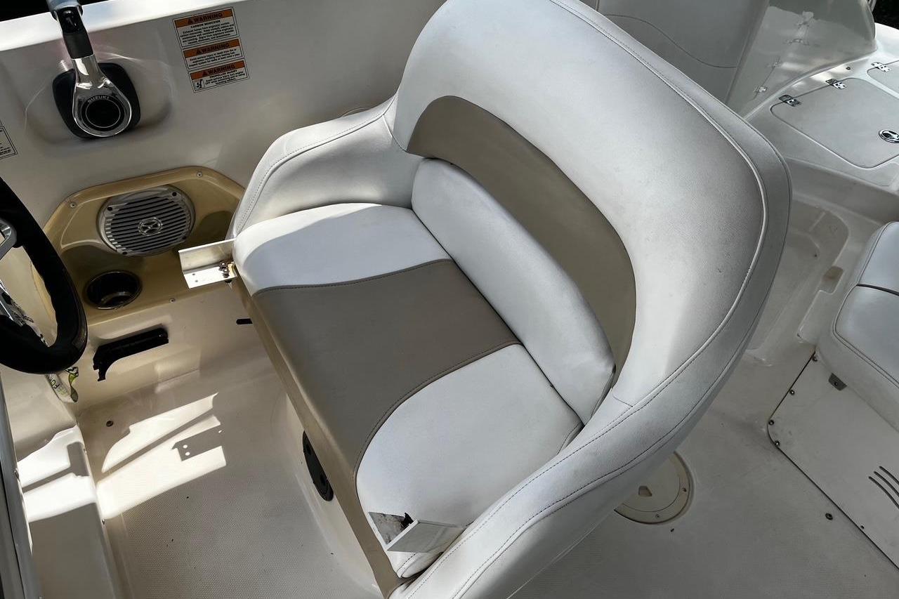 White and beige boat seat in a 2008 Hurricane FD202, featuring steering wheel and speaker.