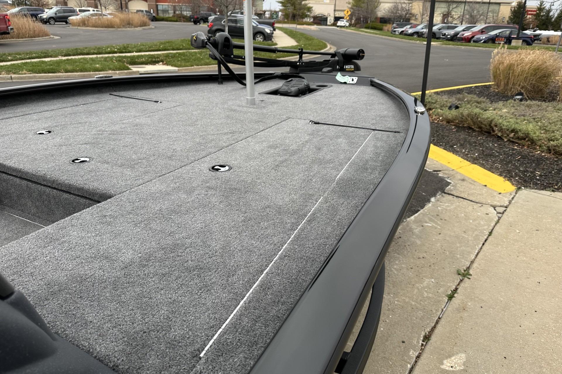 2025 Tracker Savage 215 boat deck in a parking lot, showcasing sleek design and carpeted surface.