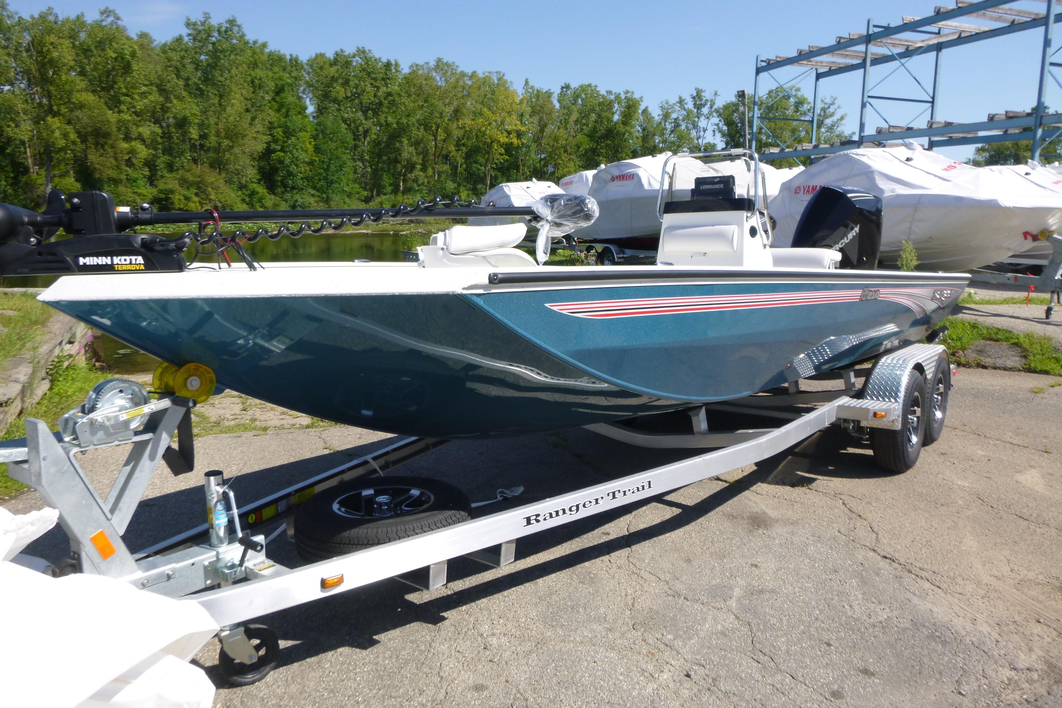 2025 Ranger RB210 boat on trailer, parked outdoors near trees and other boats.