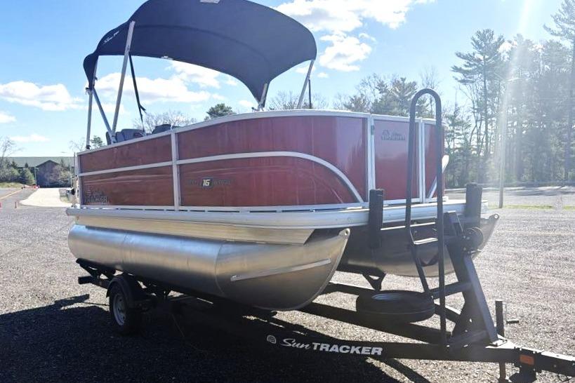 2026 Sun Tracker Party Barge 16 DLX pontoon boat on trailer, parked outdoors.