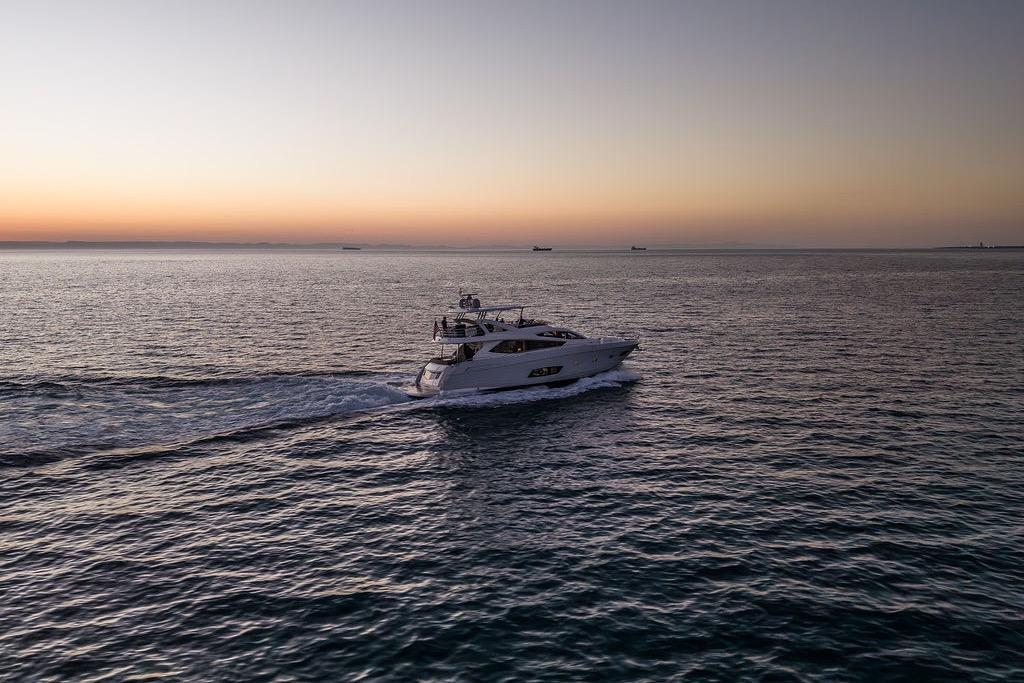 Luxurious 2012 Sunseeker Manhattan 73 yacht cruising at sunset on open sea.