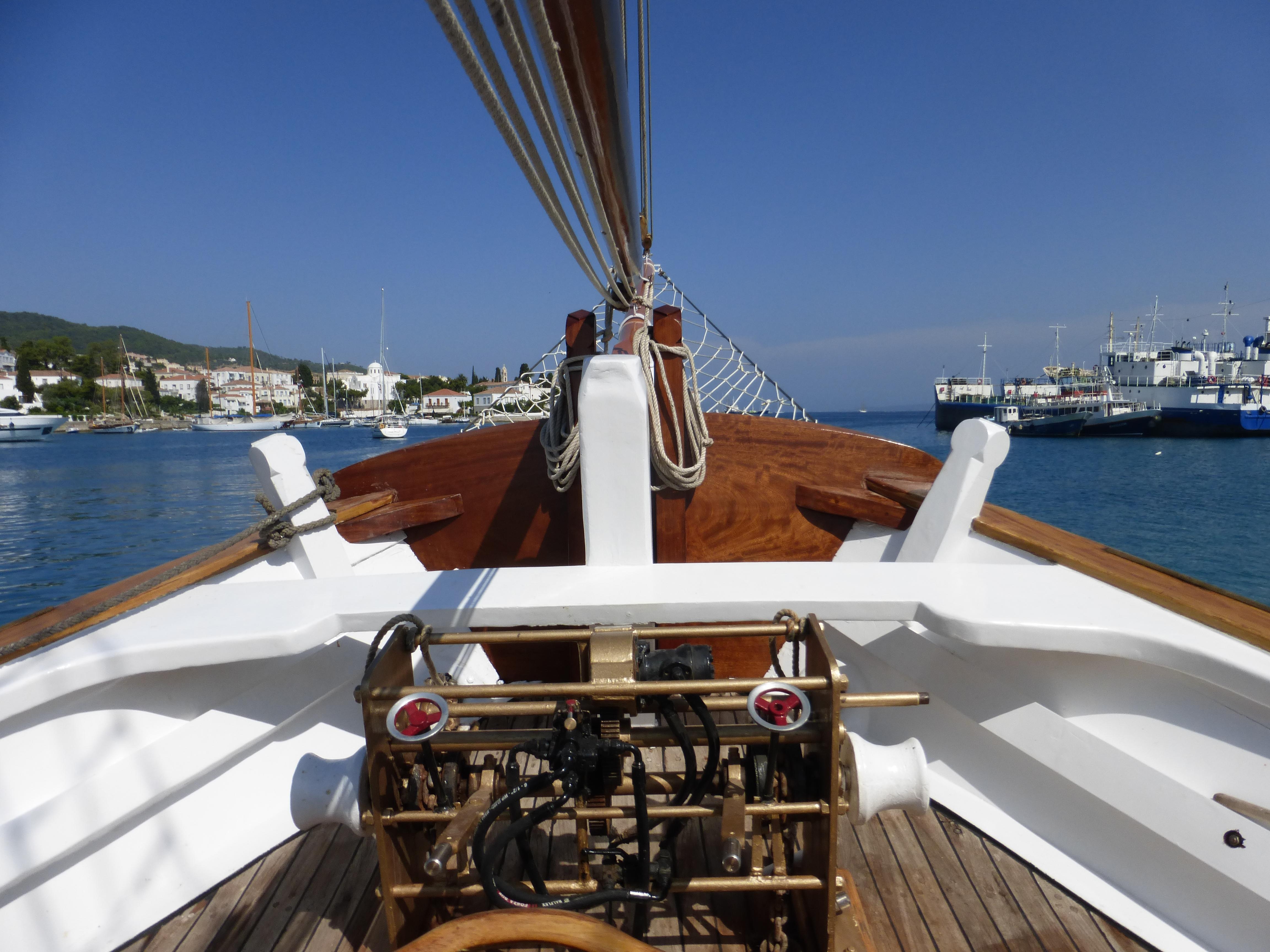 1953 Custom Perama boat deck with nautical equipment, docked in a scenic harbor.
