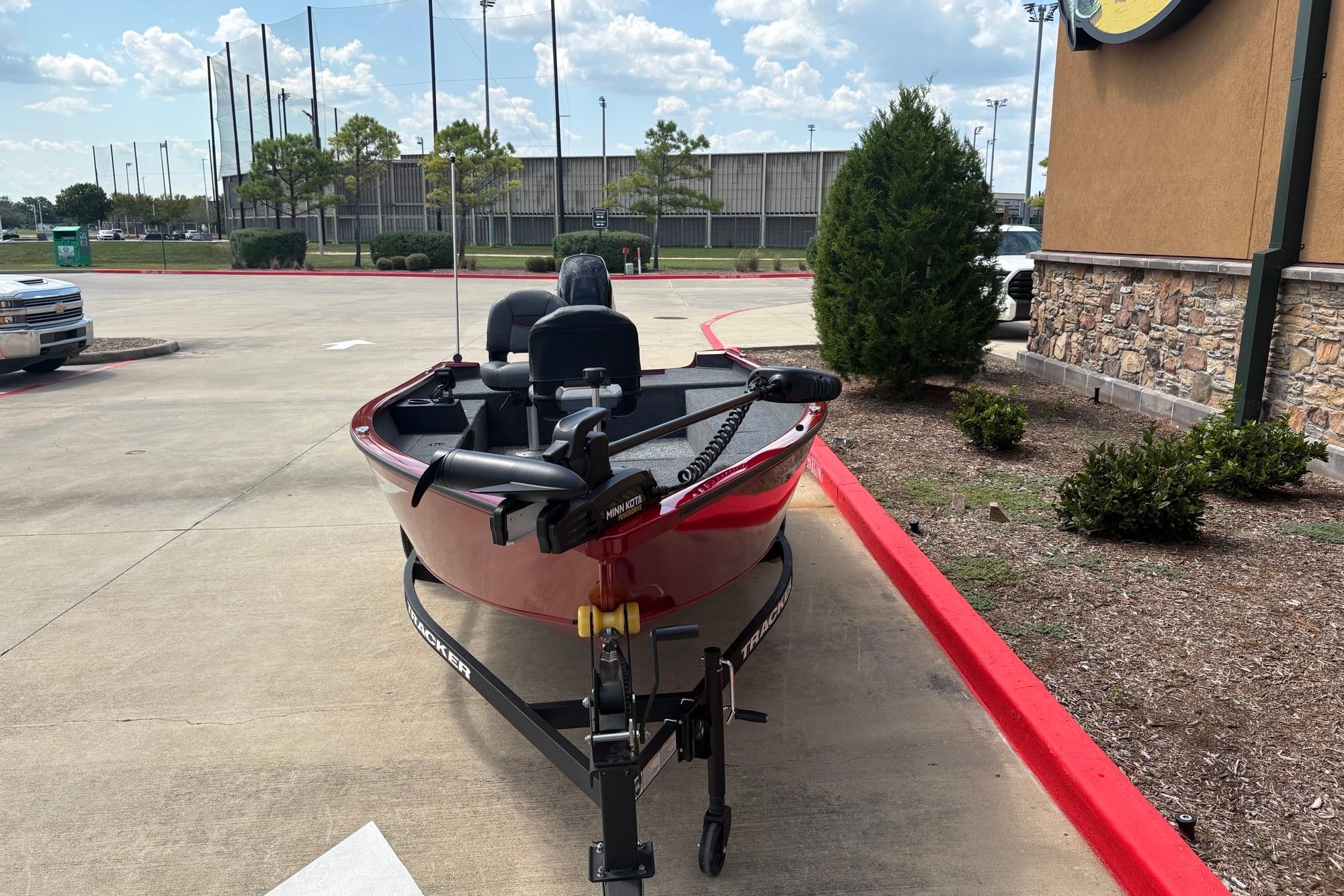 2026 Tracker Super Guide V-16 T boat on trailer in parking lot.