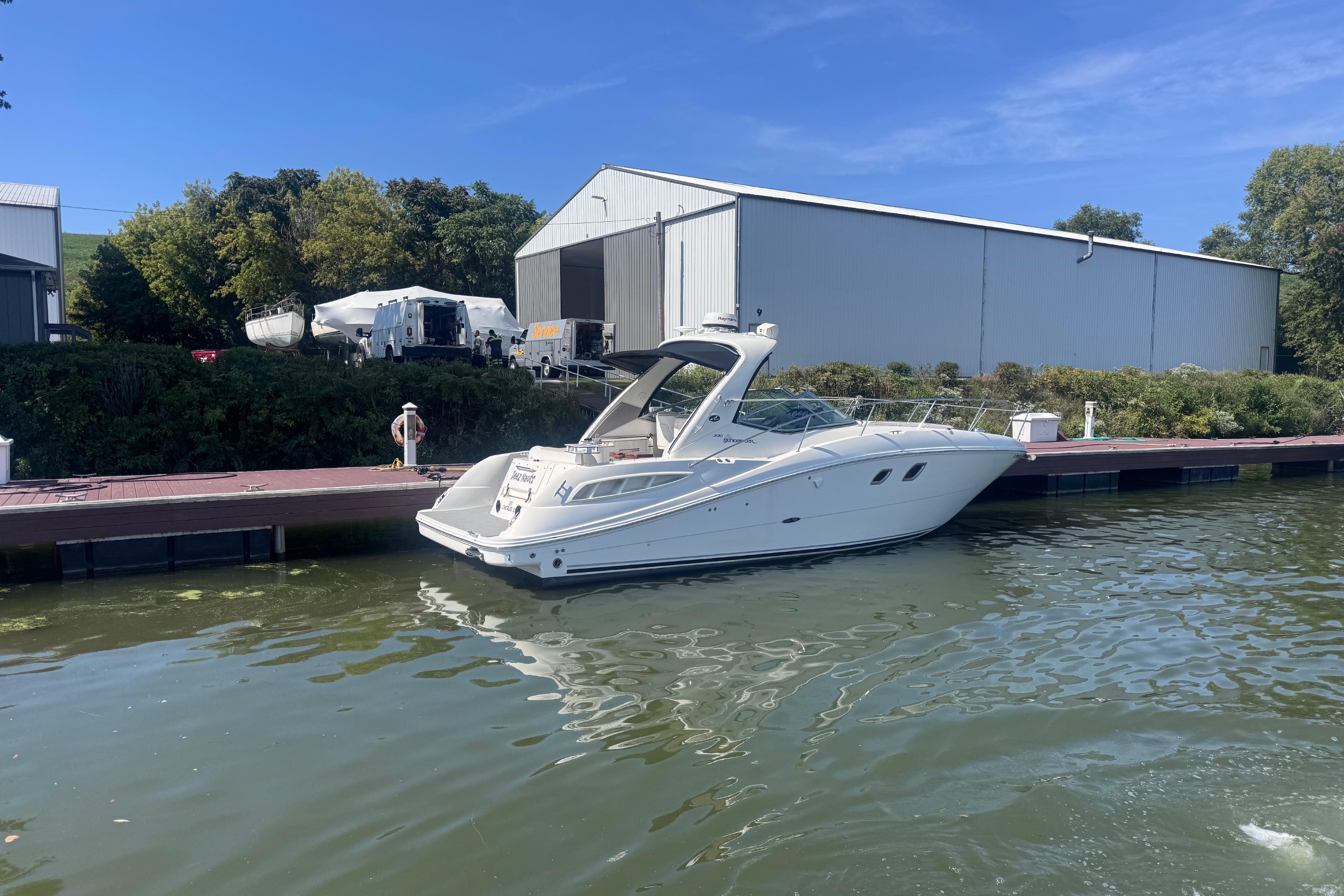 2008 Sea Ray 350 Sundancer yacht docked by a marina under clear blue skies.