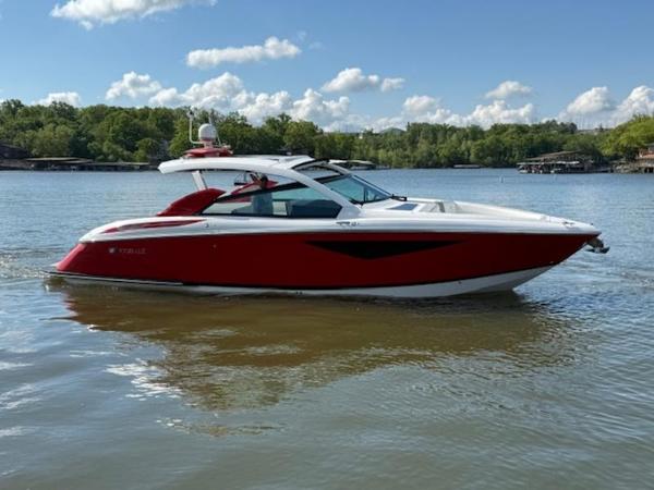 2022 Cobalt A36BR boat in red on a calm lake with trees in the background.