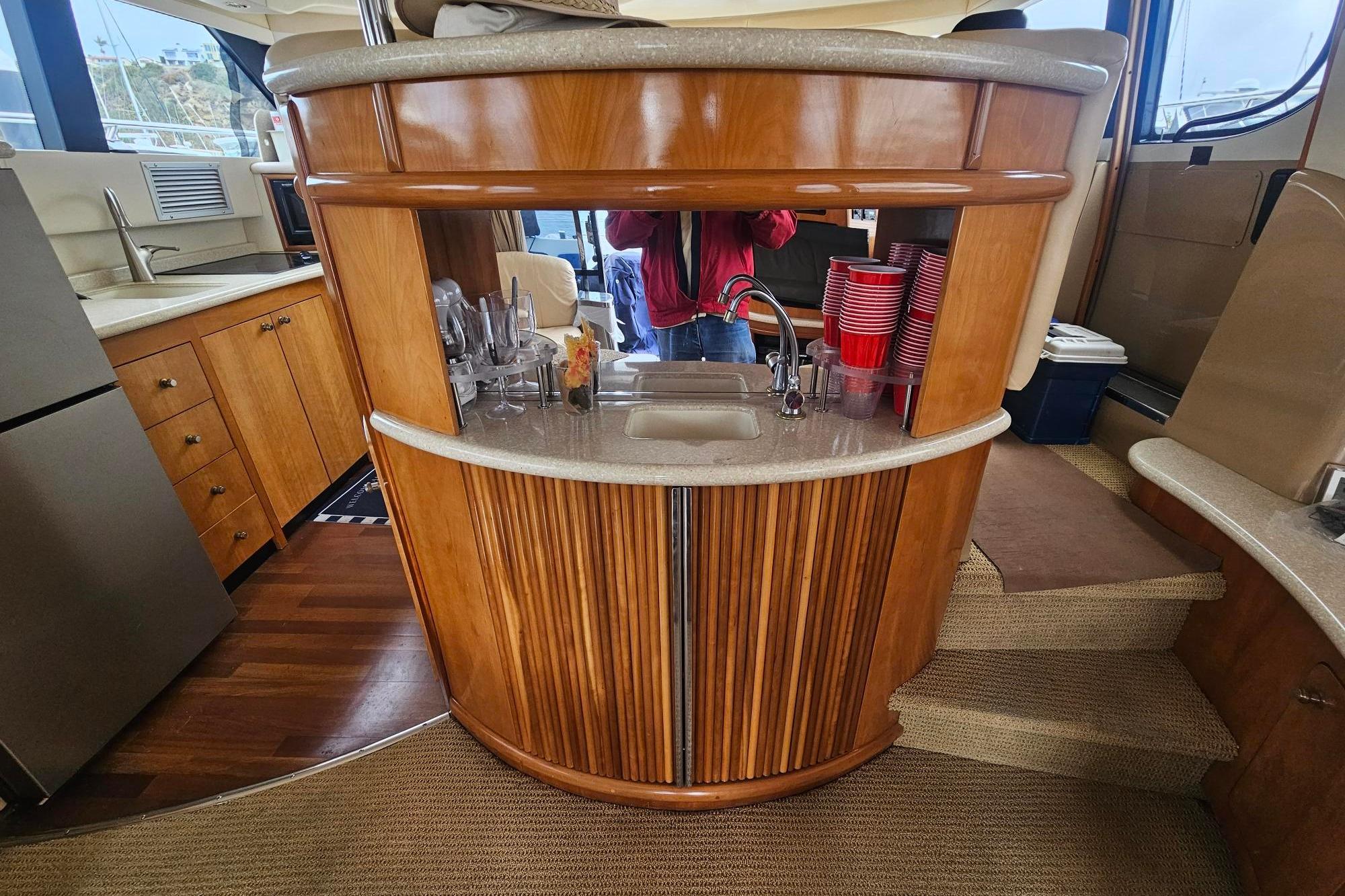 Luxurious 2002 Carver 450 Voyager Pilothouse interior with elegant wood cabinetry and compact kitchenette.