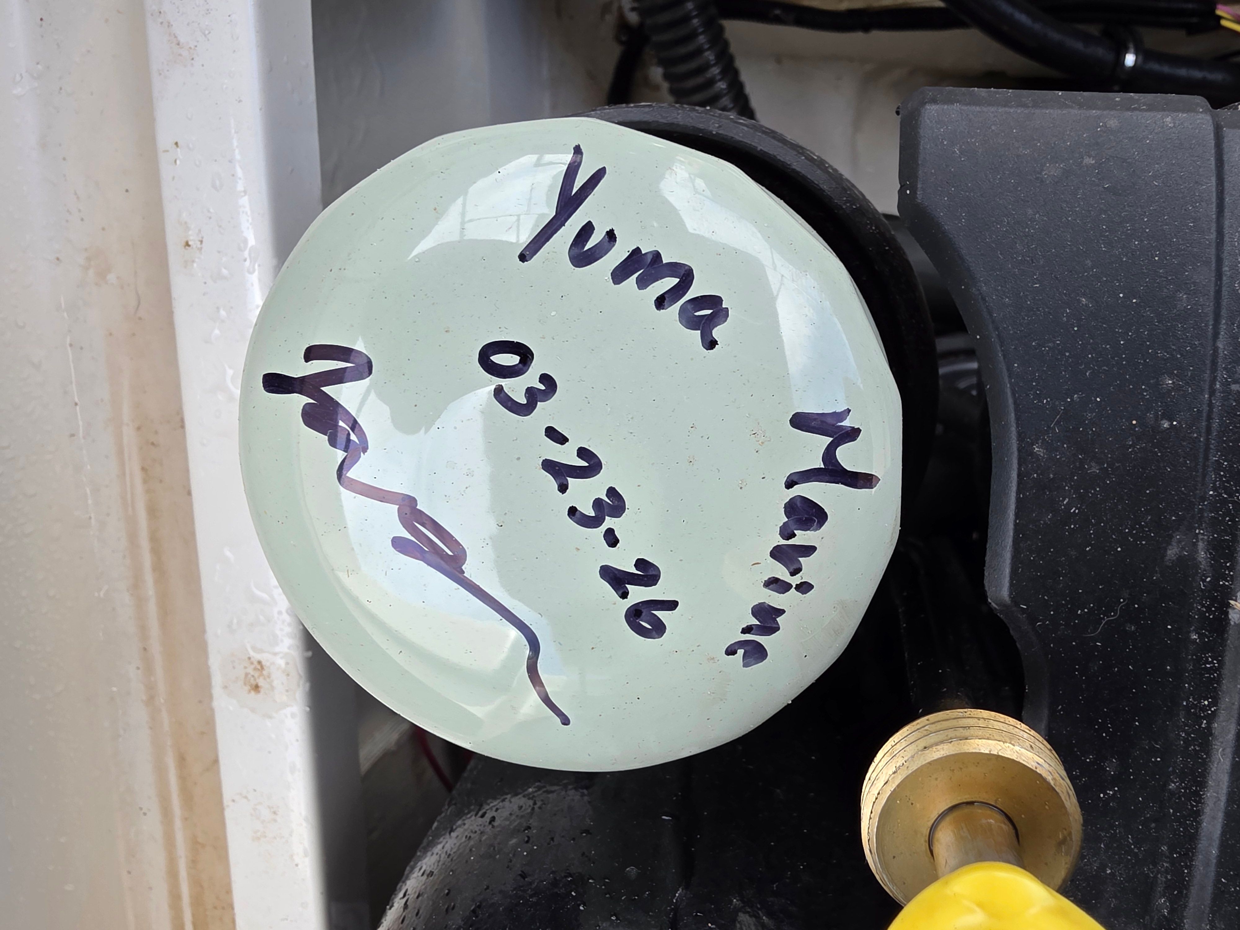 Close-up of a boat steering wheel with handwritten text on a sticker.