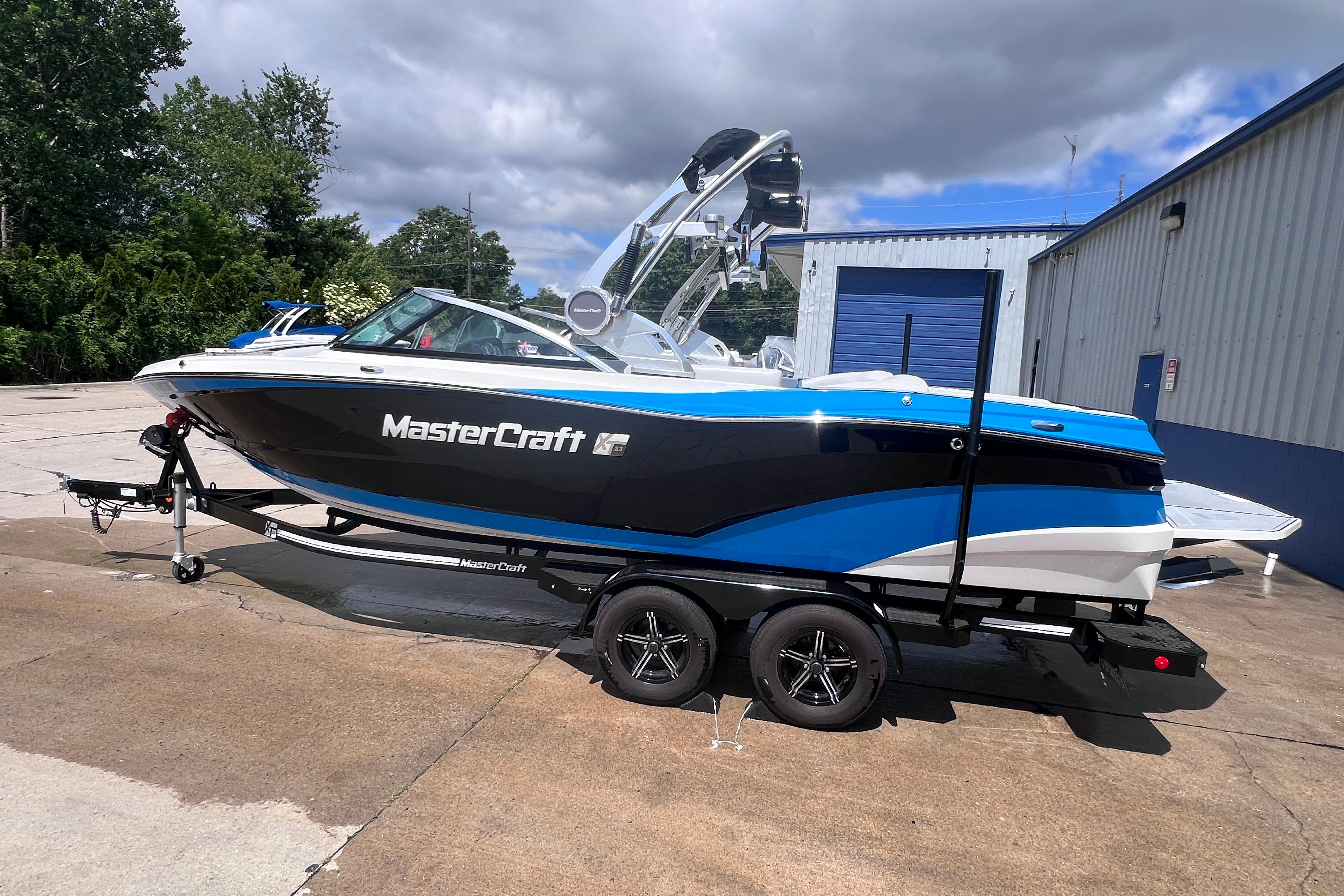 2021 MasterCraft XT23 boat on trailer, parked outdoors near a building.