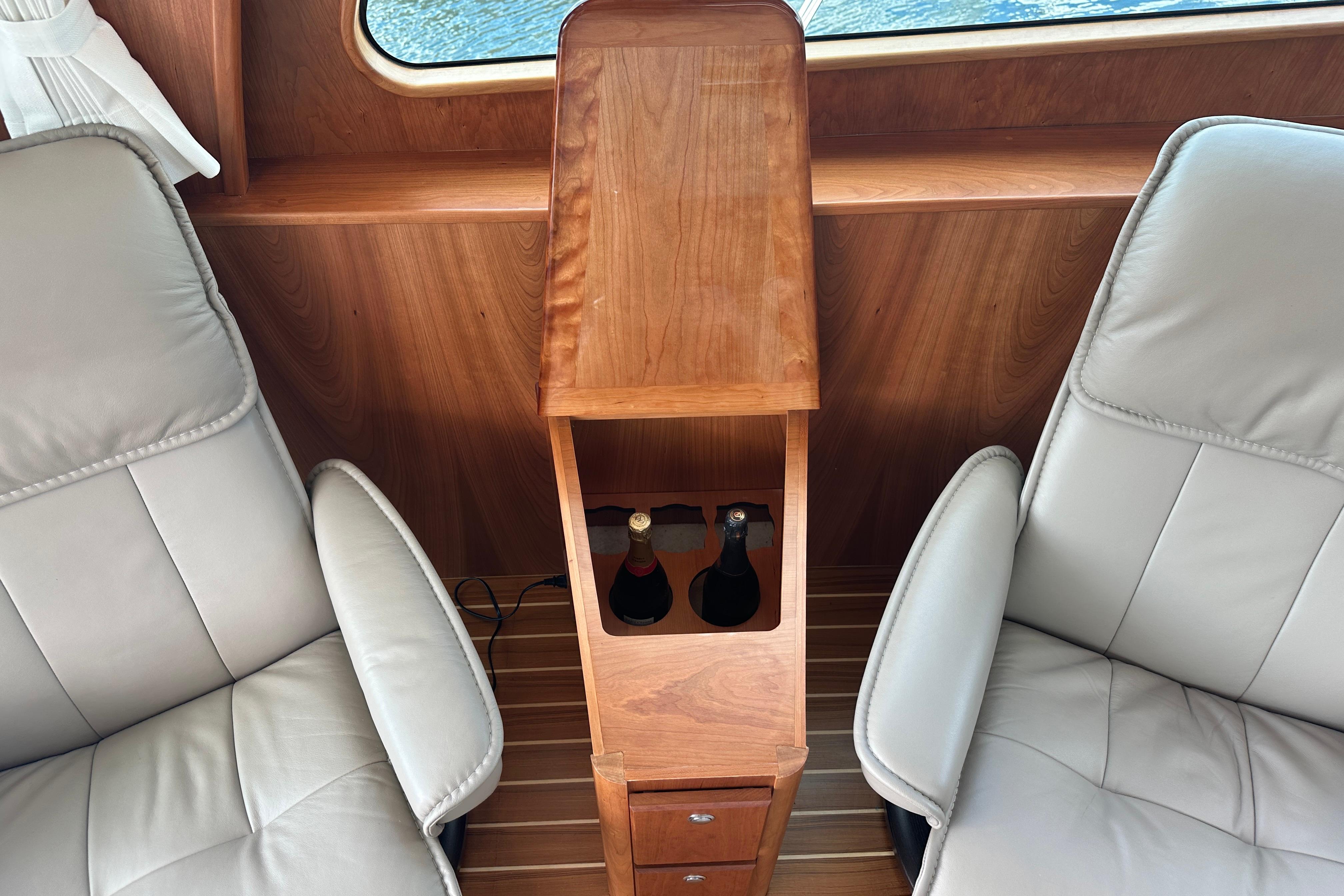 Interior of 2025 Sabre 48 Salon Express with leather seats and wooden bottle holder.