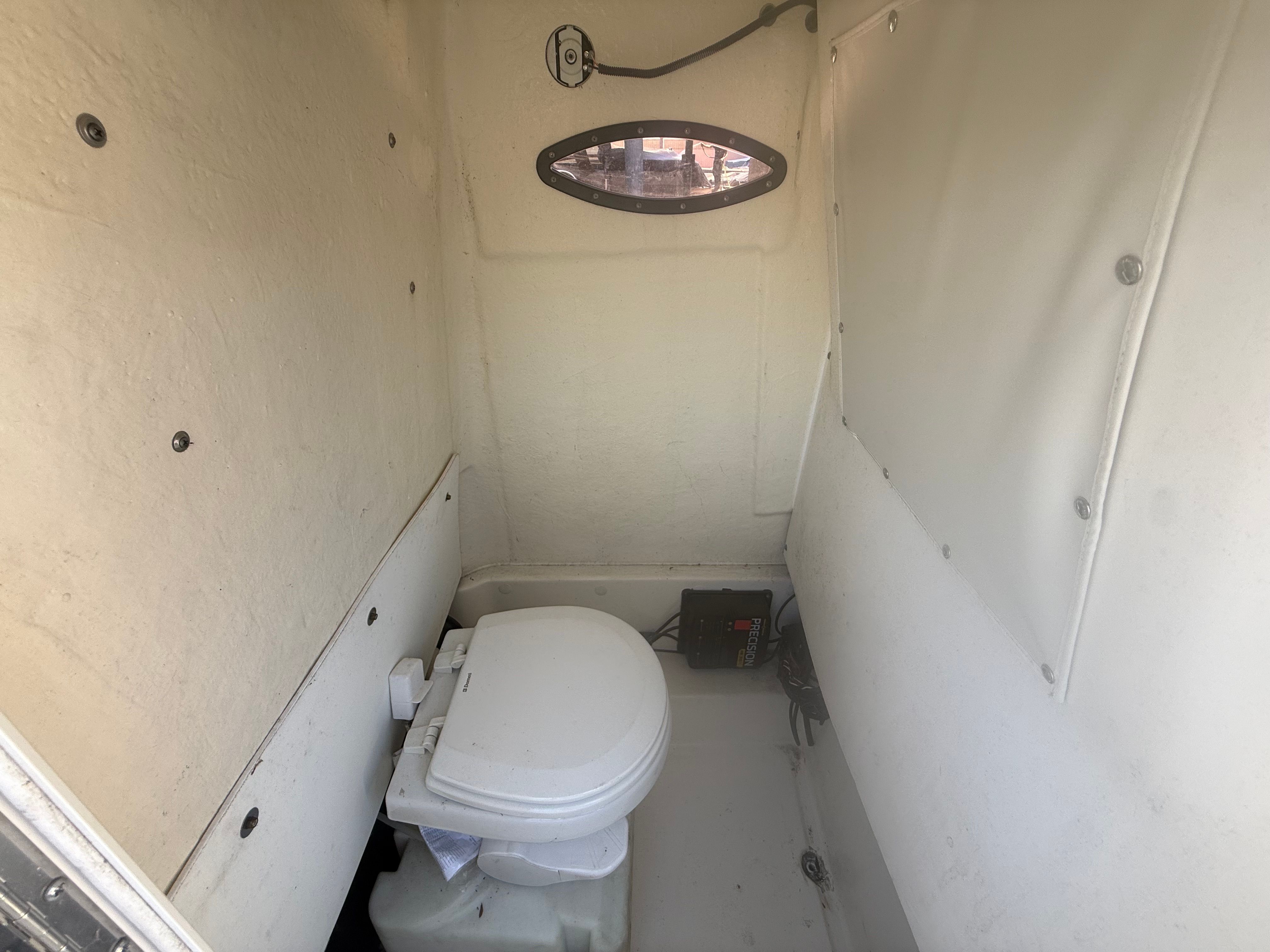 Interior of a boat cabin with a toilet and small window.