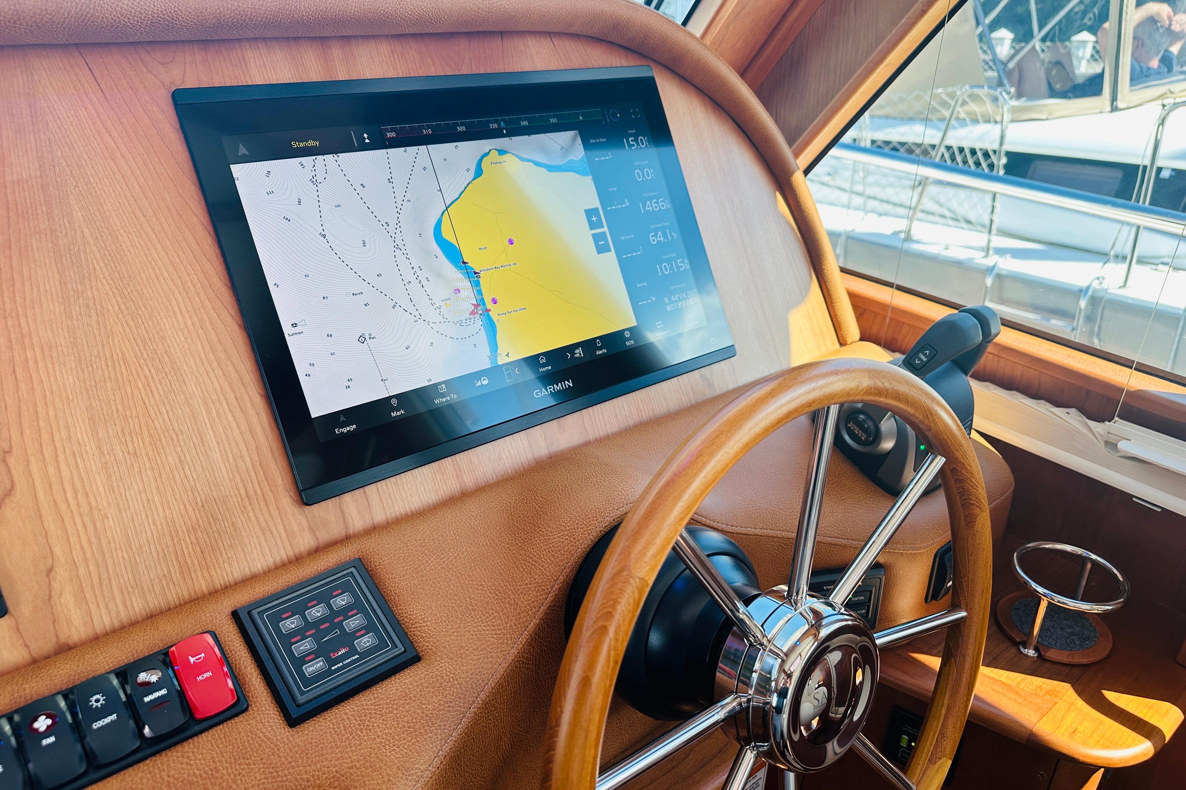 Helm of 2025 Sabre 48 Salon Express with navigation display and wooden steering wheel.