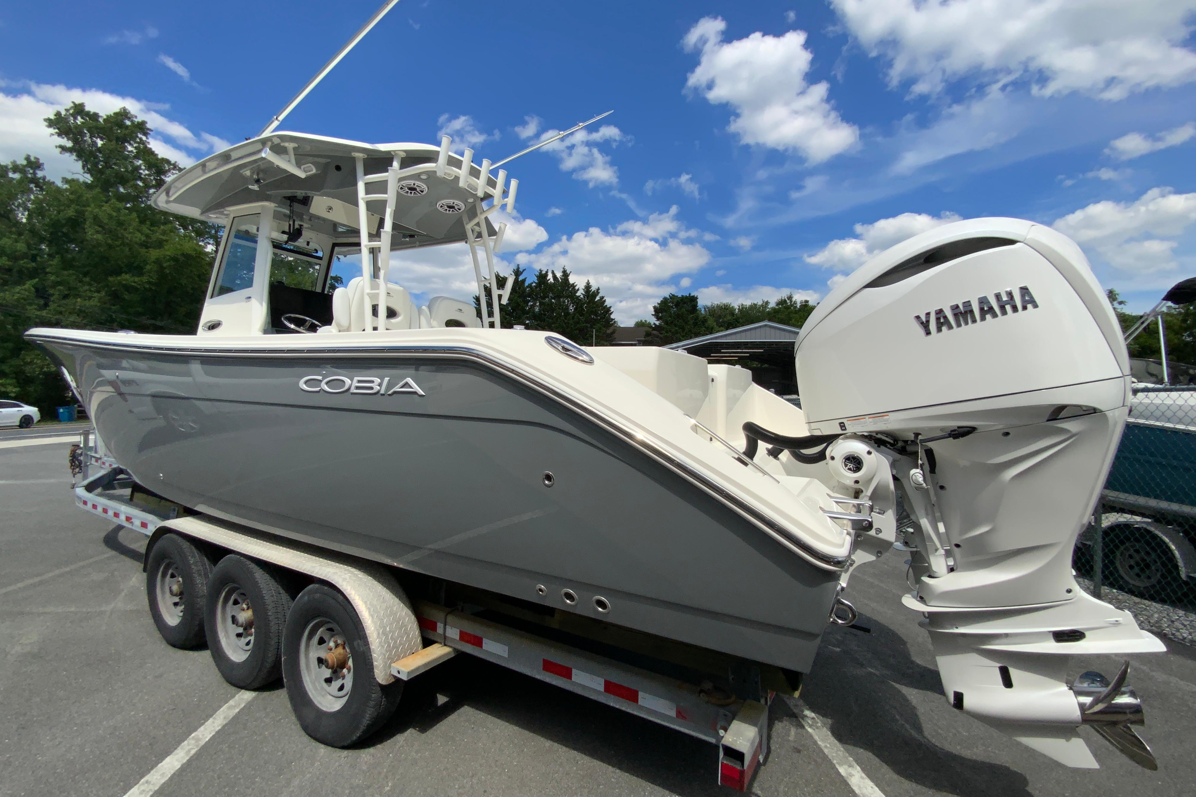2027 Cobia 320 Center Console boat with Yamaha engine on trailer under blue sky.