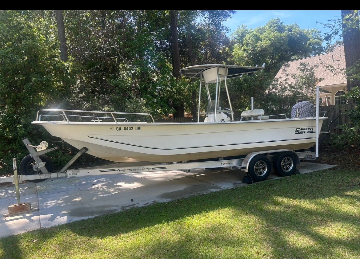 2011 Carolina Skiff 258 DLV boat on trailer in yard.