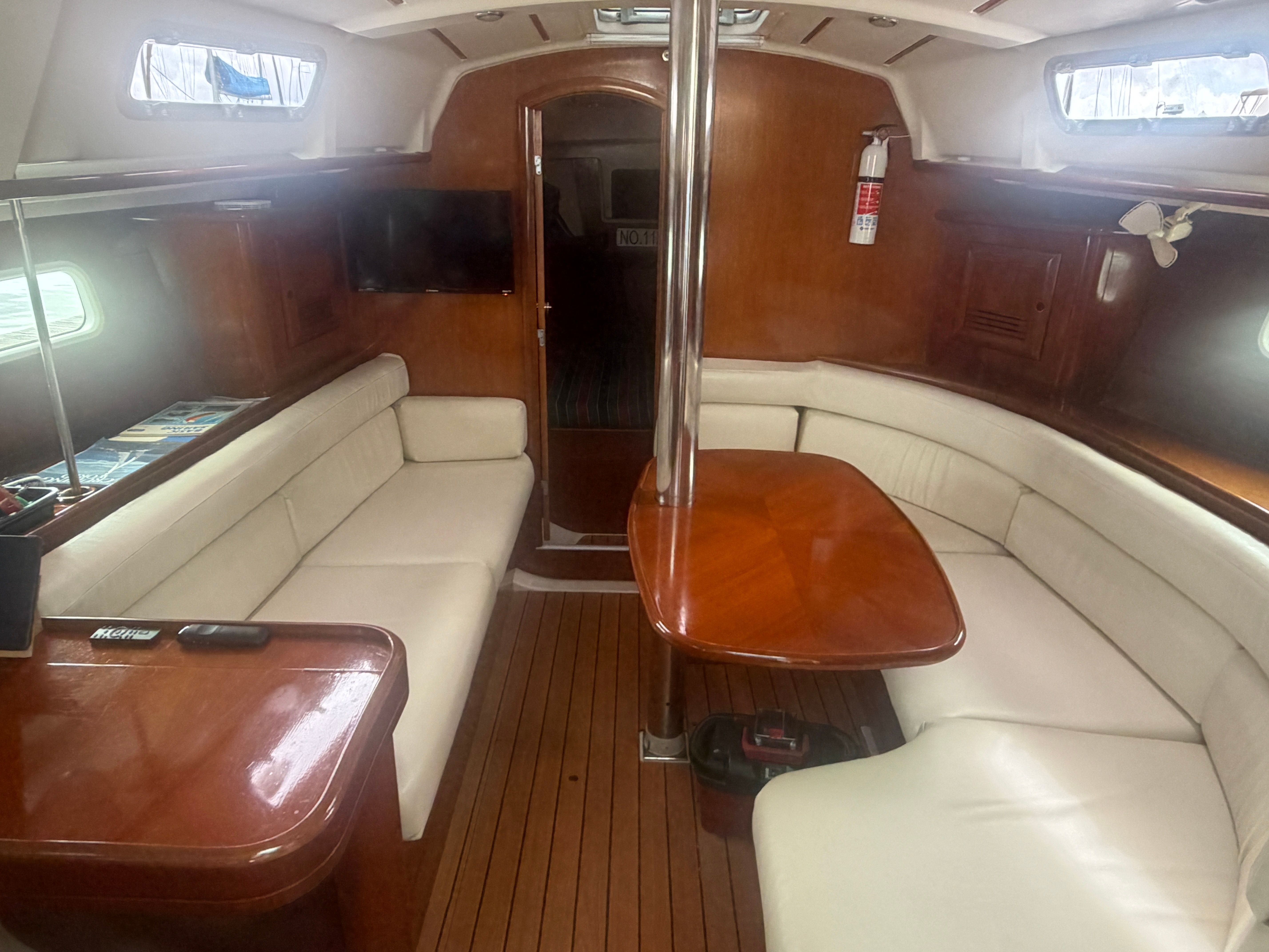 Interior of a 2000 Beneteau Oceanis 361 with wooden table and white seating.