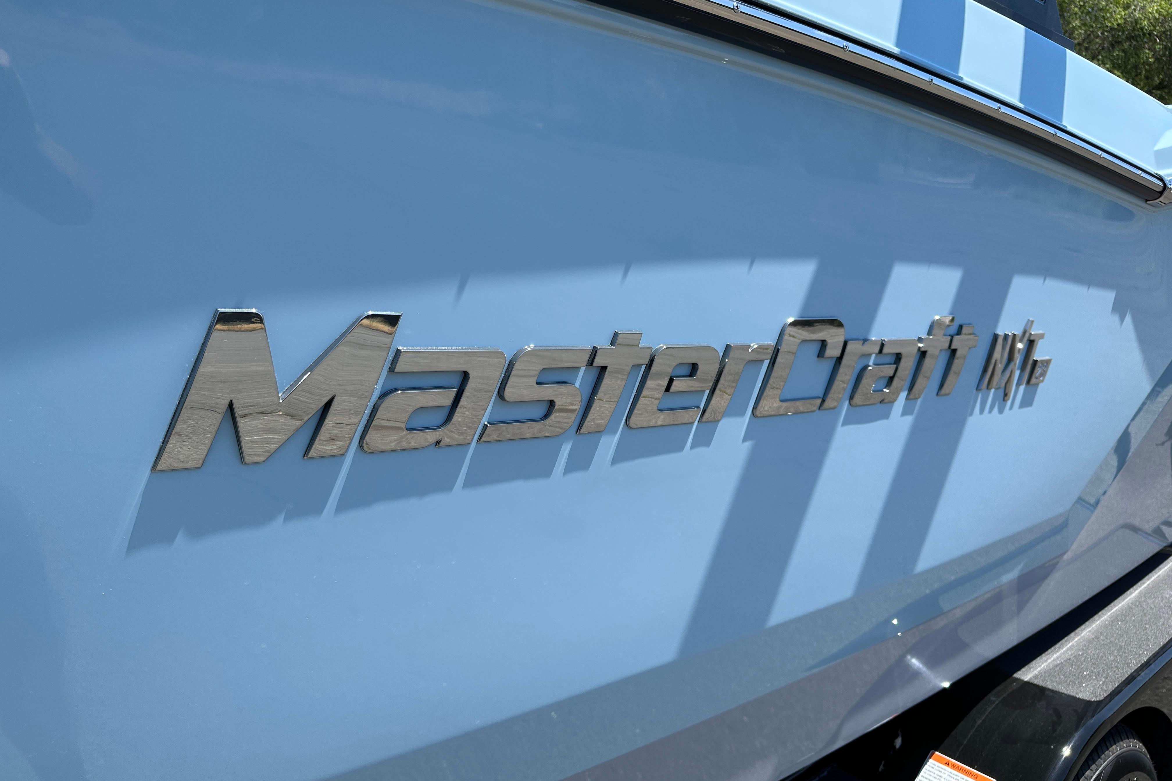 2023 MasterCraft NXT23 boat with metallic logo on blue hull.
