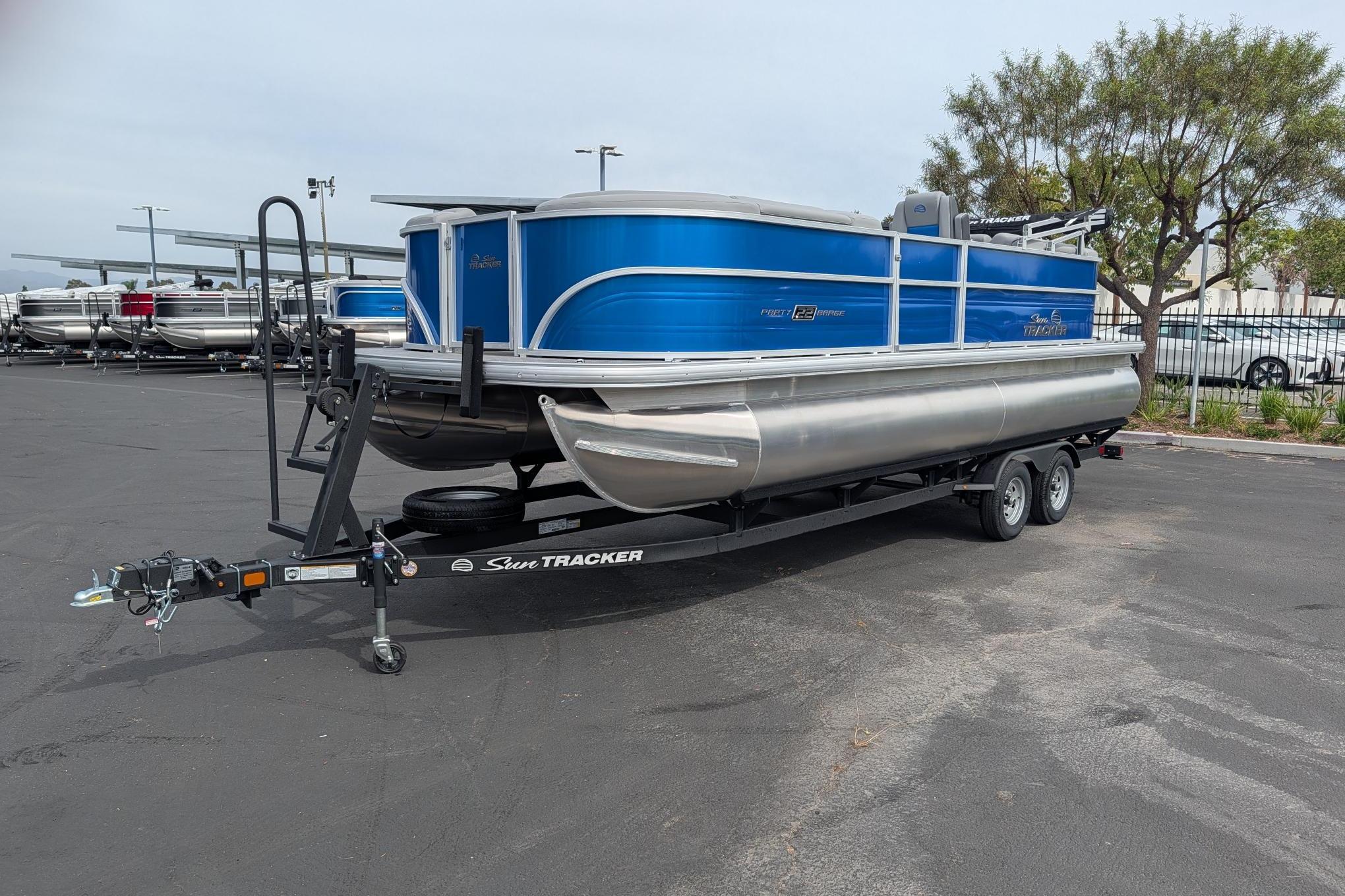 2026 Sun Tracker Party Barge 22 DLX pontoon boat on trailer in parking lot.