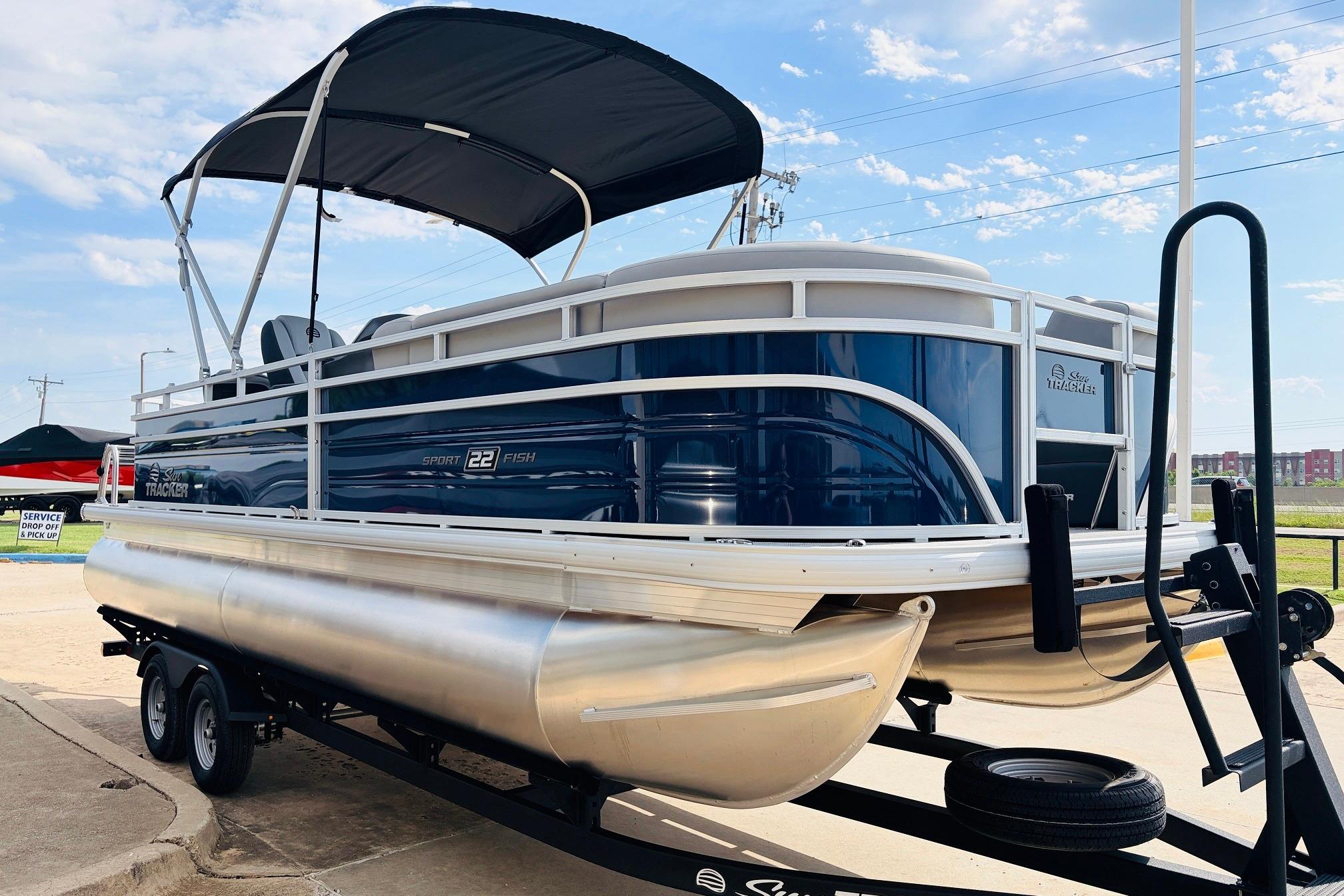 2026 Sun Tracker SportFish 22 DLX pontoon boat on trailer, featuring sleek design and canopy.