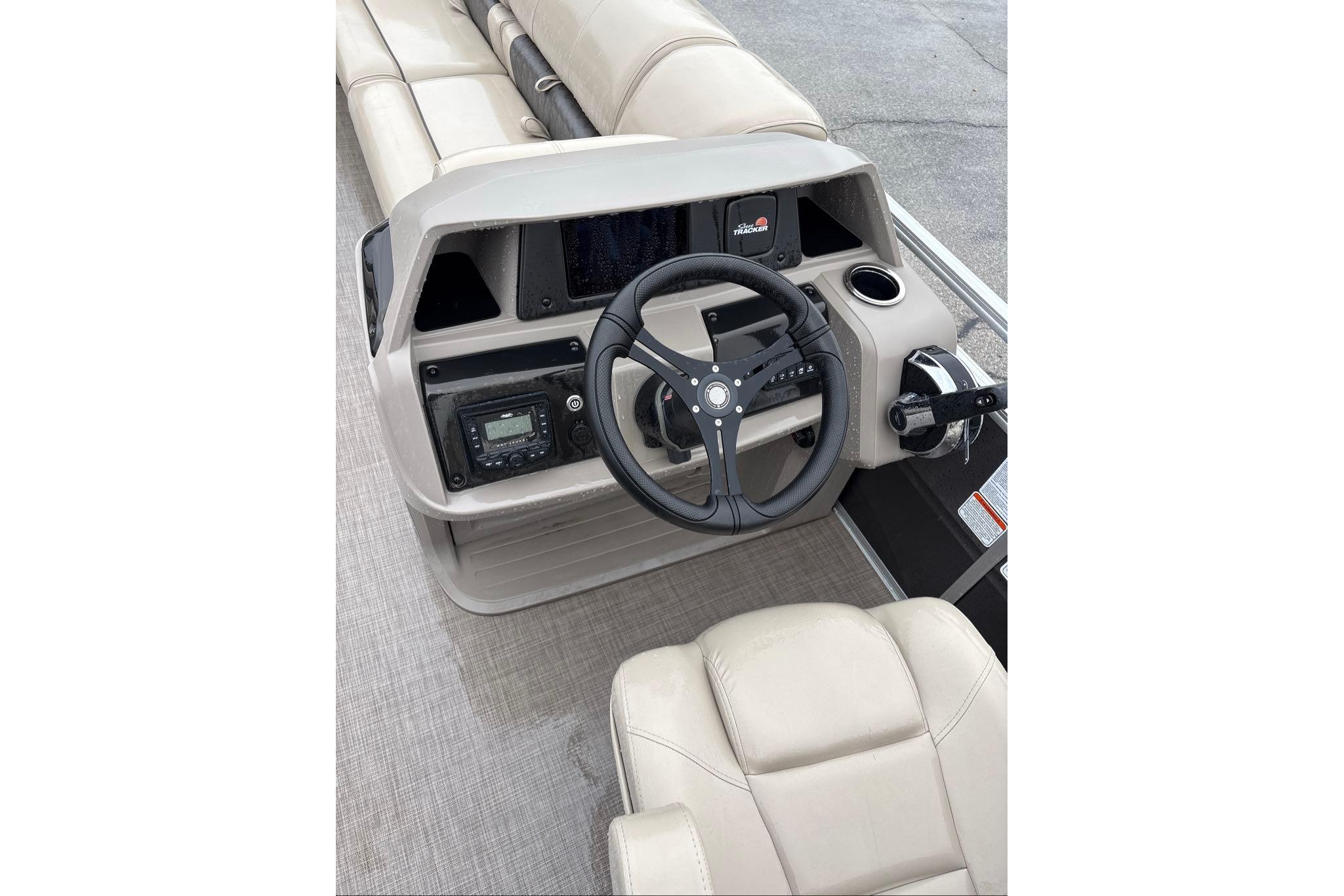 2024 Sun Tracker Party Barge 24 DLX steering console with beige seating and controls.