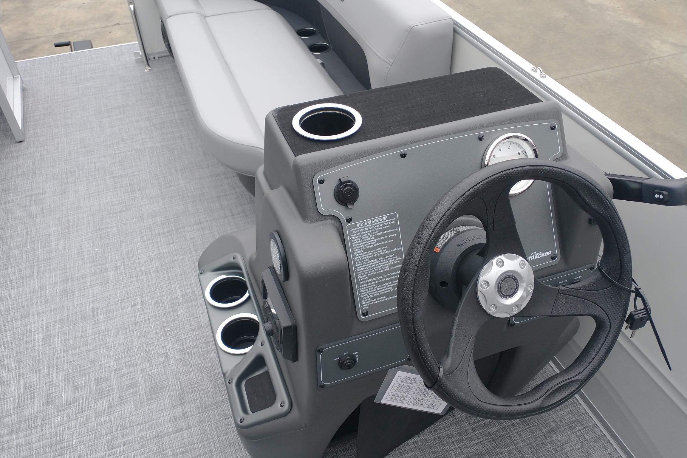 2026 Sun Tracker Party Barge 16 DLX steering console with cup holders and seating.