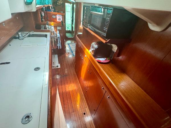 Interior of 1996 Beneteau Oceanis 40 CC yacht with wooden cabinetry and modern appliances.