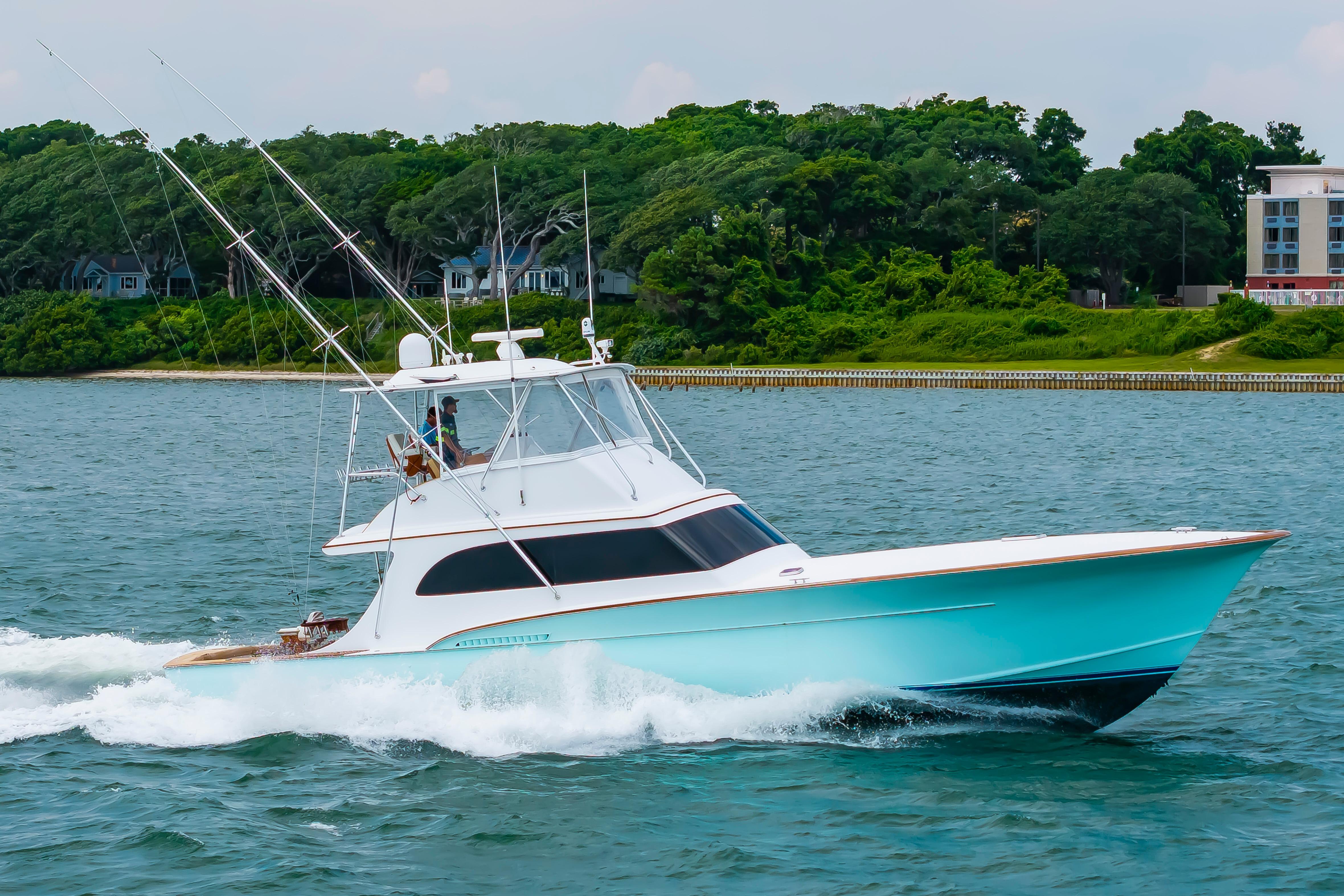 Custom Carolina Scarborough 56 Convertible yacht cruising on water, 1993 model, with lush greenery backdrop.