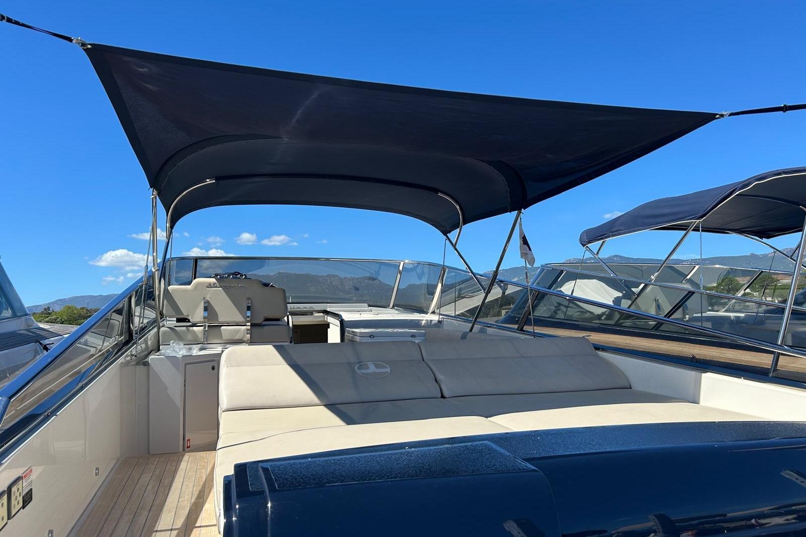 2019 Itama 45s yacht with sunshade, sleek design, and spacious deck under clear blue sky.