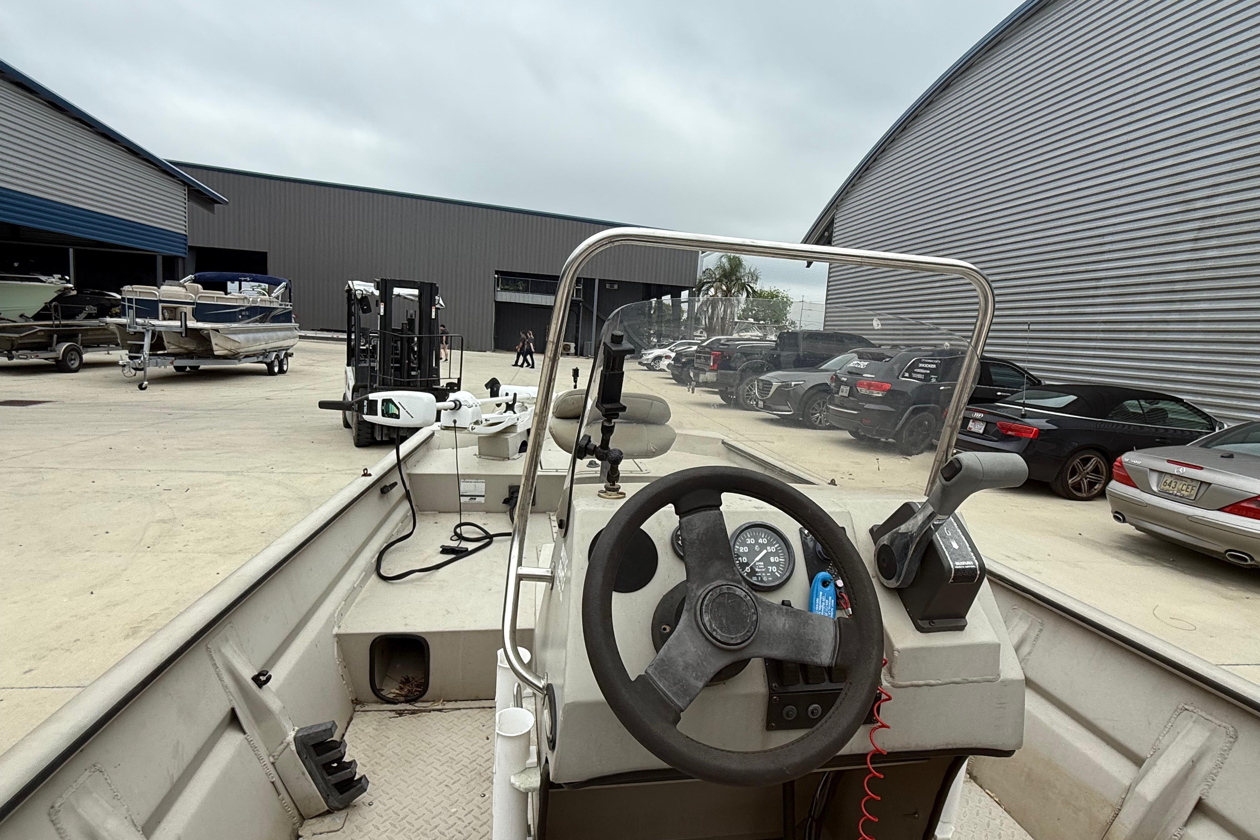 2008 SeaArk 1652 MV boat interior with steering wheel, parked near warehouse and vehicles.