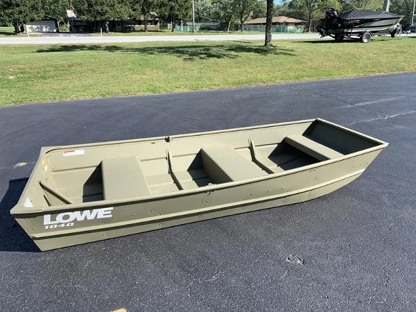 2024 Lowe L1040 Jon boat on asphalt, surrounded by grass and trees.