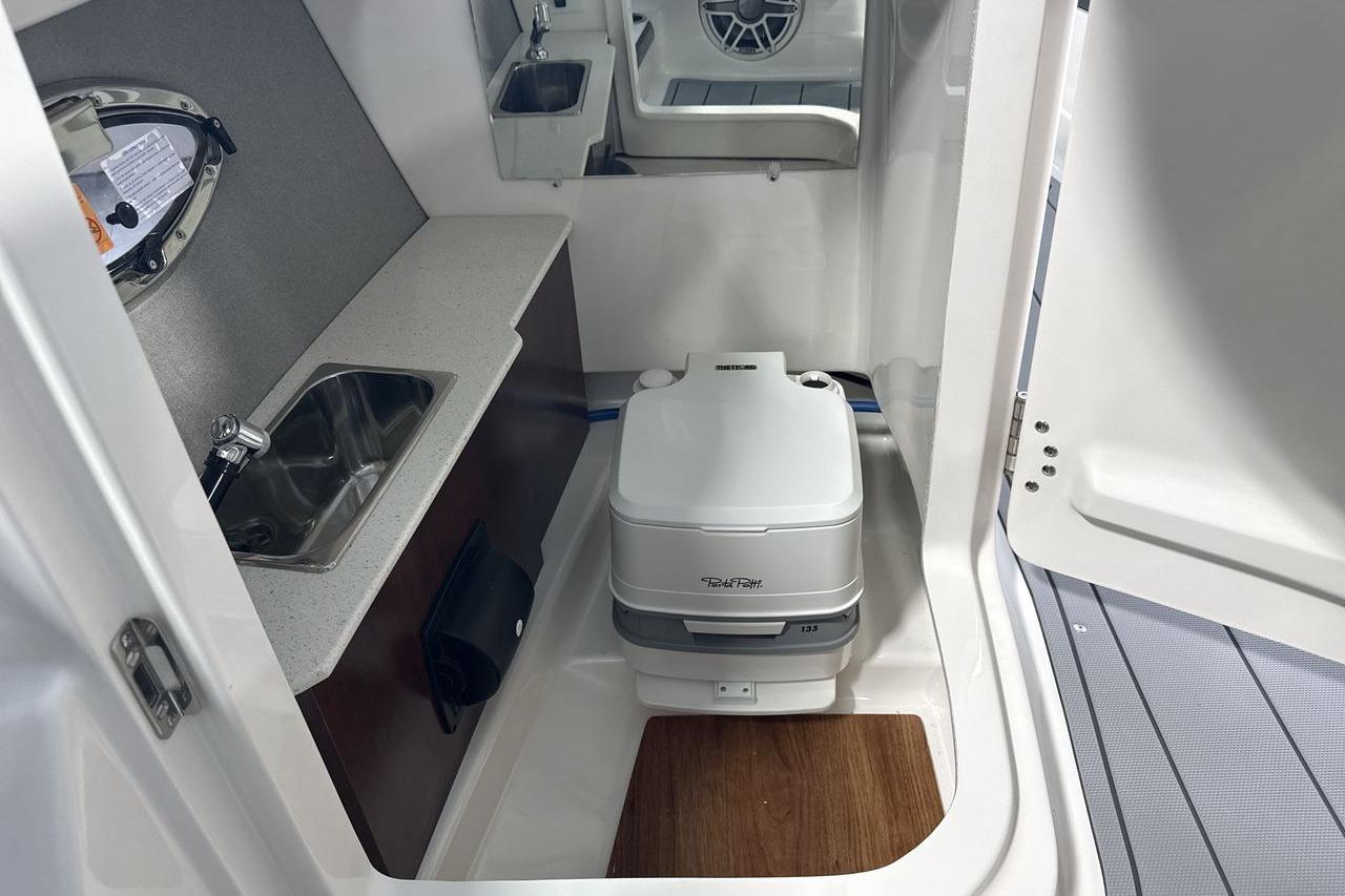 Interior view of a boat cabin with a sink and portable toilet.