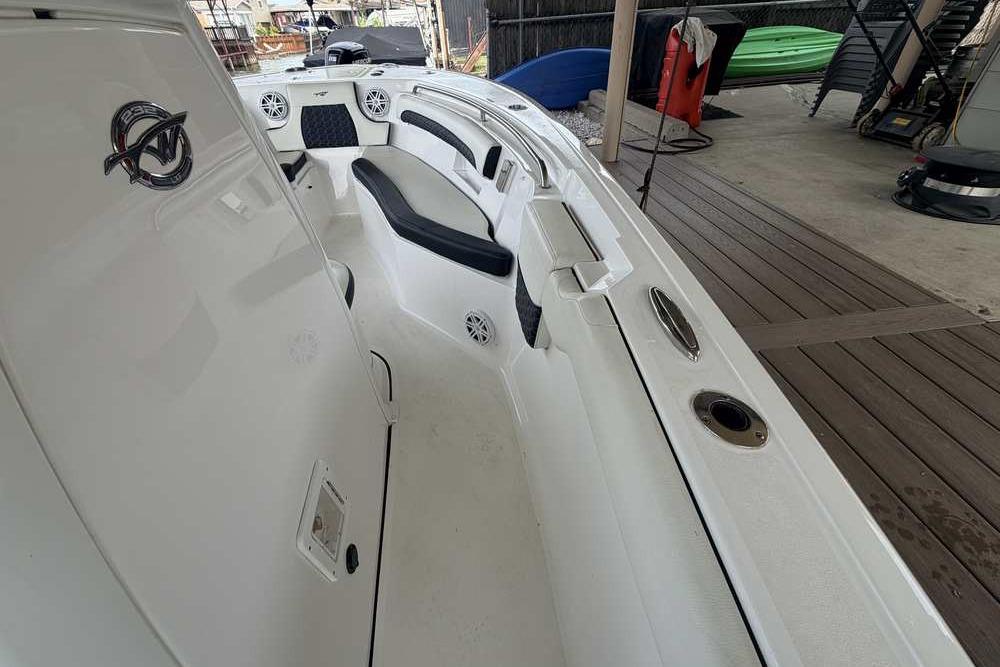 2024 Tidewater 232 LXF boat interior with seating and speakers, docked in a marina.